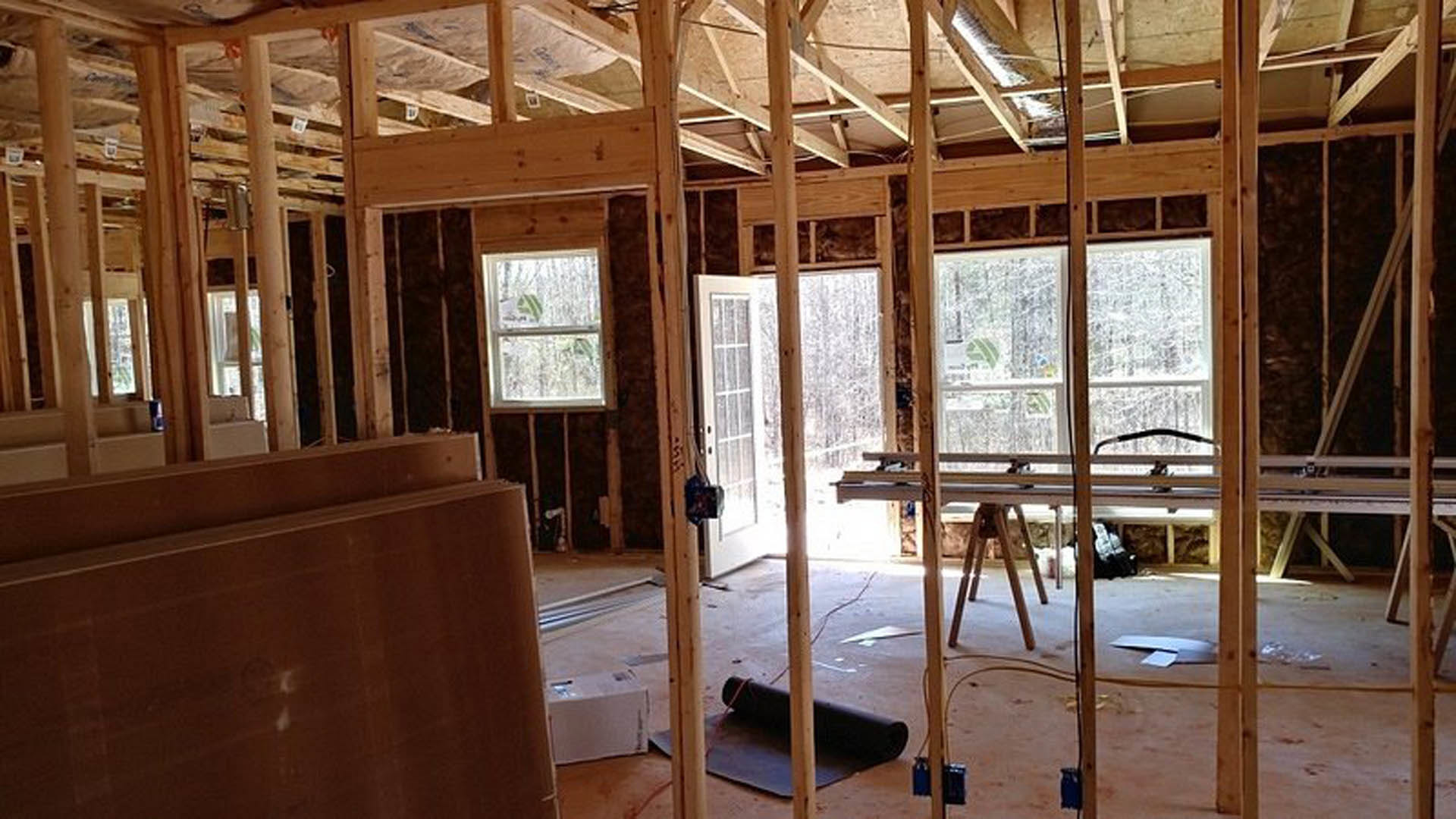 Dining area with white-stained wood paneling, exposed ceiling beams, wooden post, rectangular table, and large window with white frame
