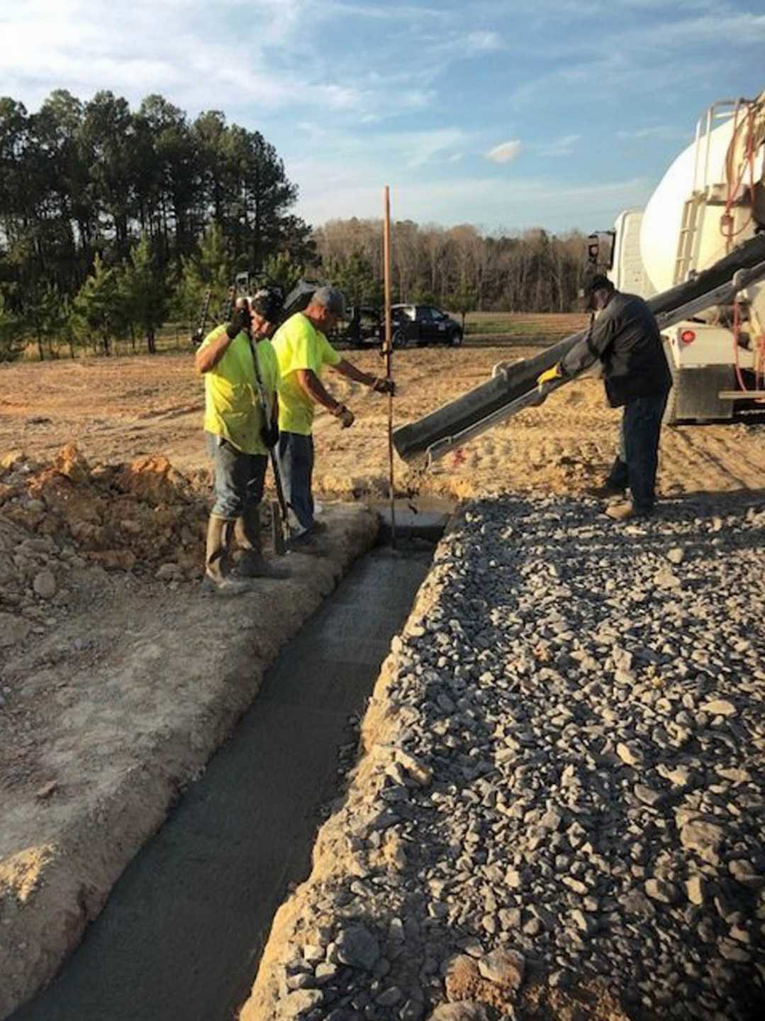 A group of men standing next to a drainage ditch.