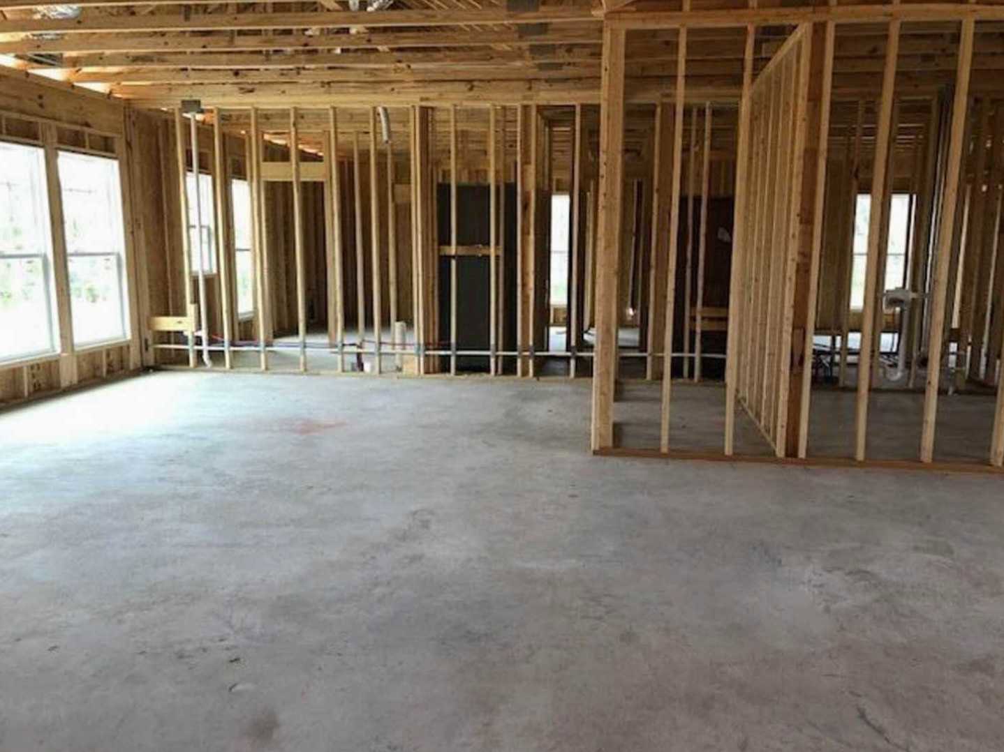 Concrete floor with exposed wood framing, wooden ceiling featuring square cutouts, large window providing natural light
