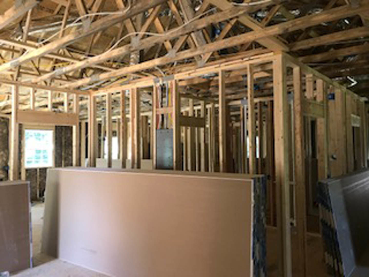 Sunlit room with exposed wood ceiling beams, white walls, and a large window