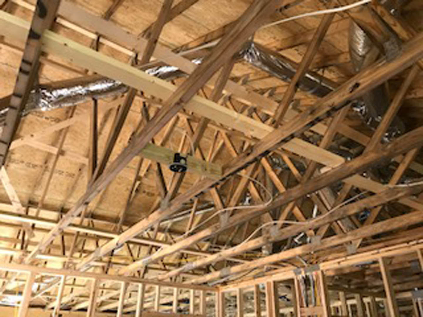 Exposed wooden ceiling beams with visible insulation, steel supports, and electrical wiring; ceiling fan mounted centrally