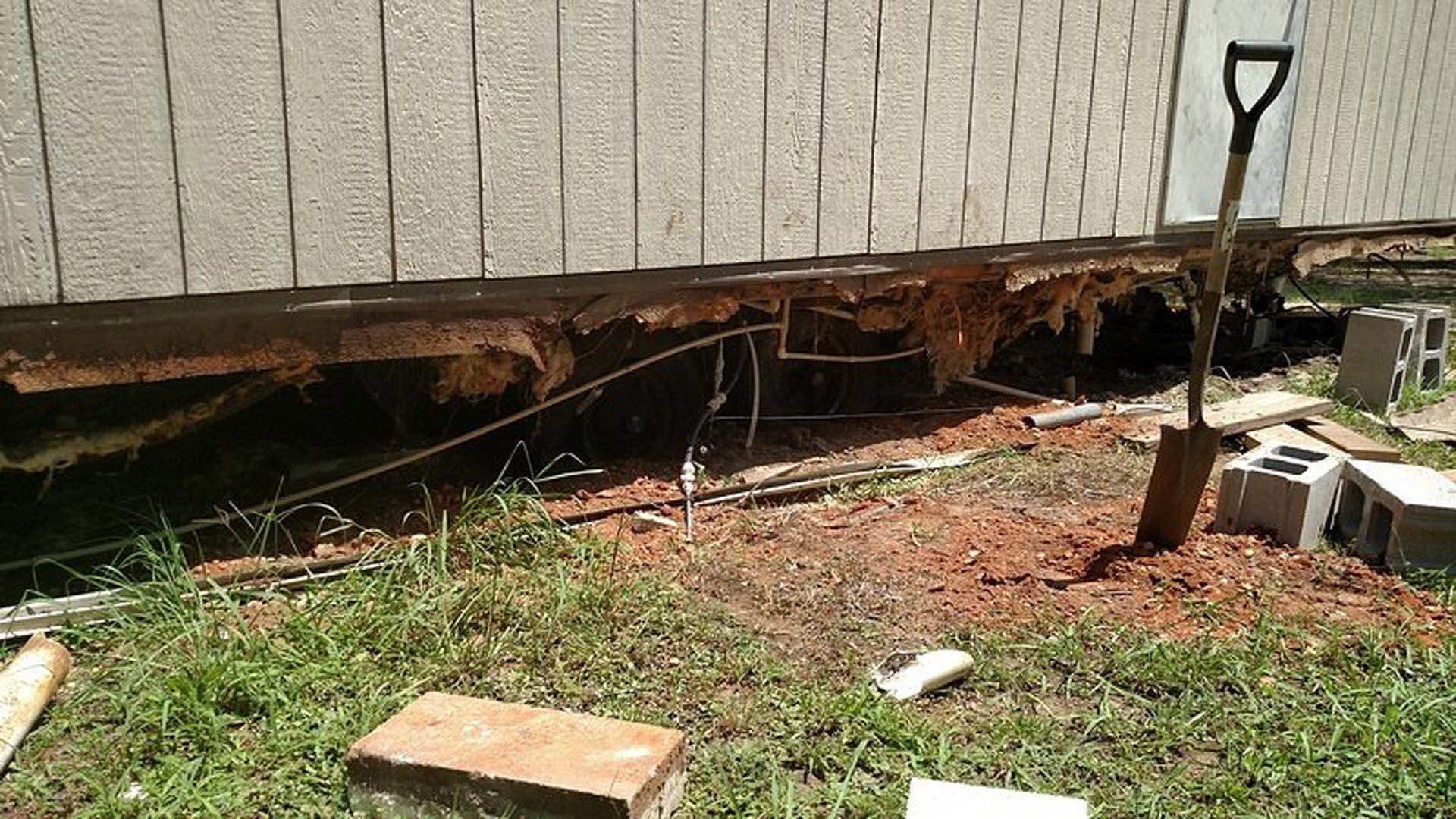 Modern home exterior with grassy yard, concrete block embedded in ground featuring circular holes, surrounded by plants and outdoor landscaping
