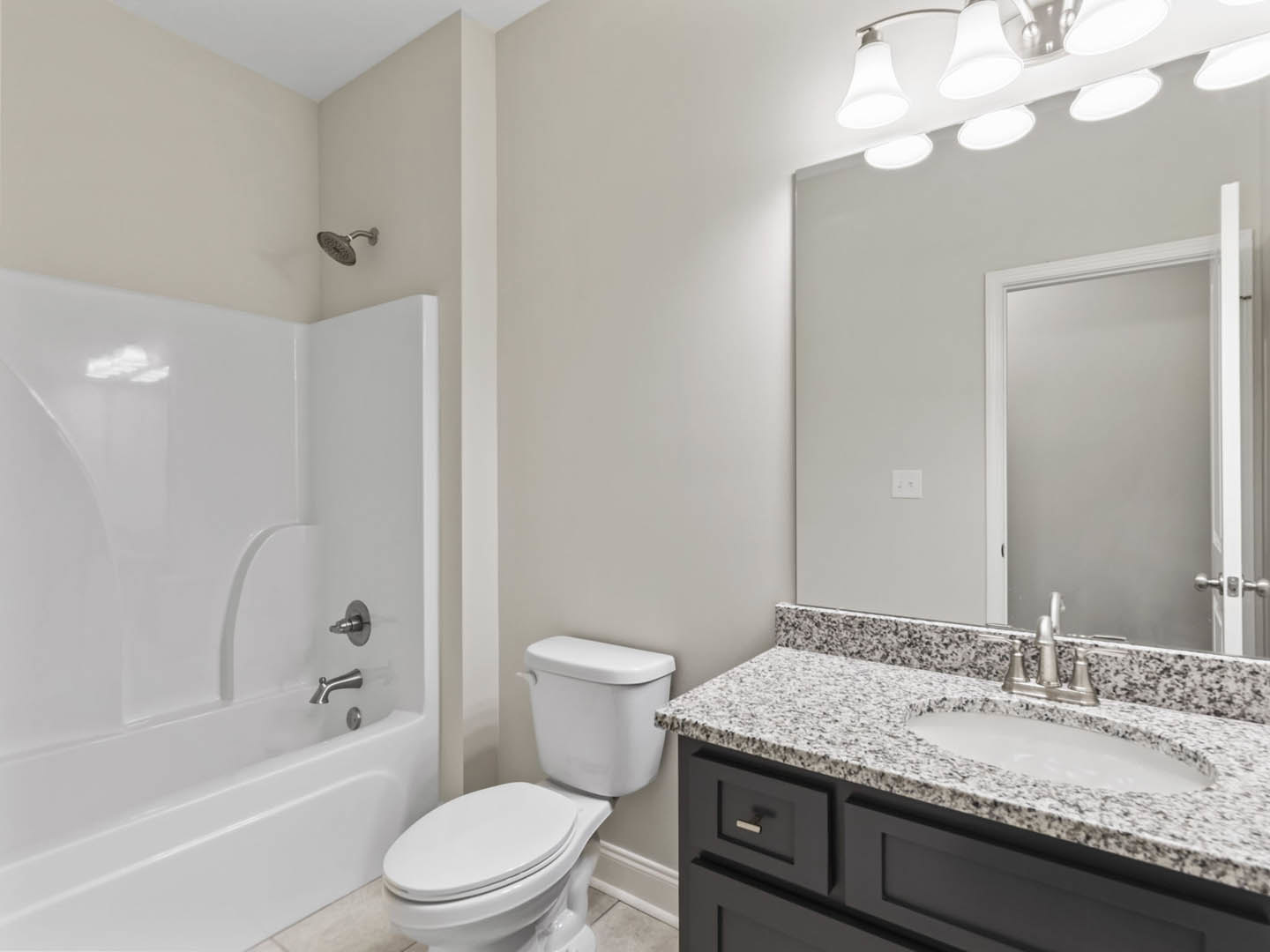Bathroom with white tile walls, modern sink with chrome faucet, wall-mounted mirror, white toilet, built-in bathtub, and overhead shower fixture