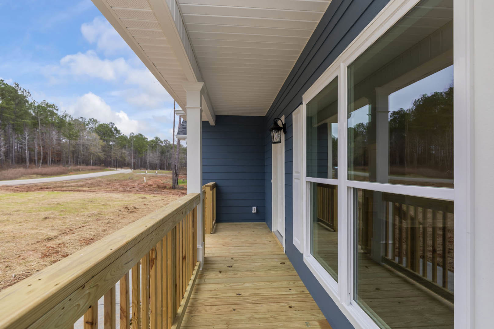 Wood deck with wooden railing, blue exterior walls, outdoor lamp, and Kimbell Art Museum visible in the background under a partly cloudy sky.