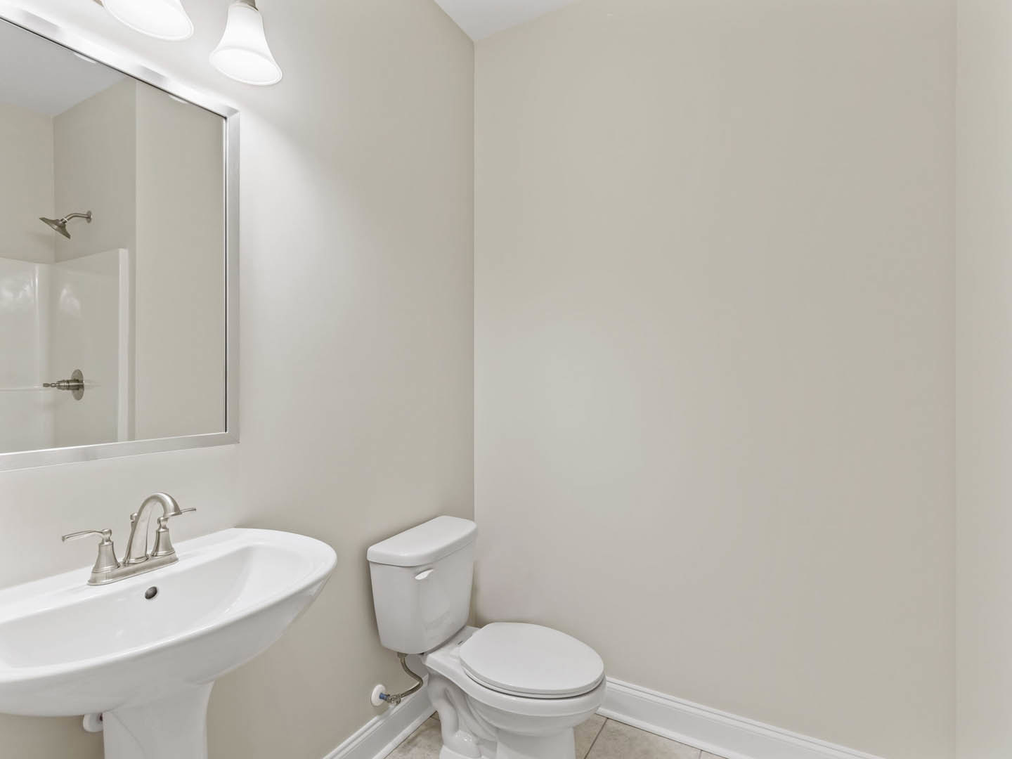 Modern bathroom with white porcelain toilet, rectangular sink with chrome faucet, tiled walls, and glass shower enclosure