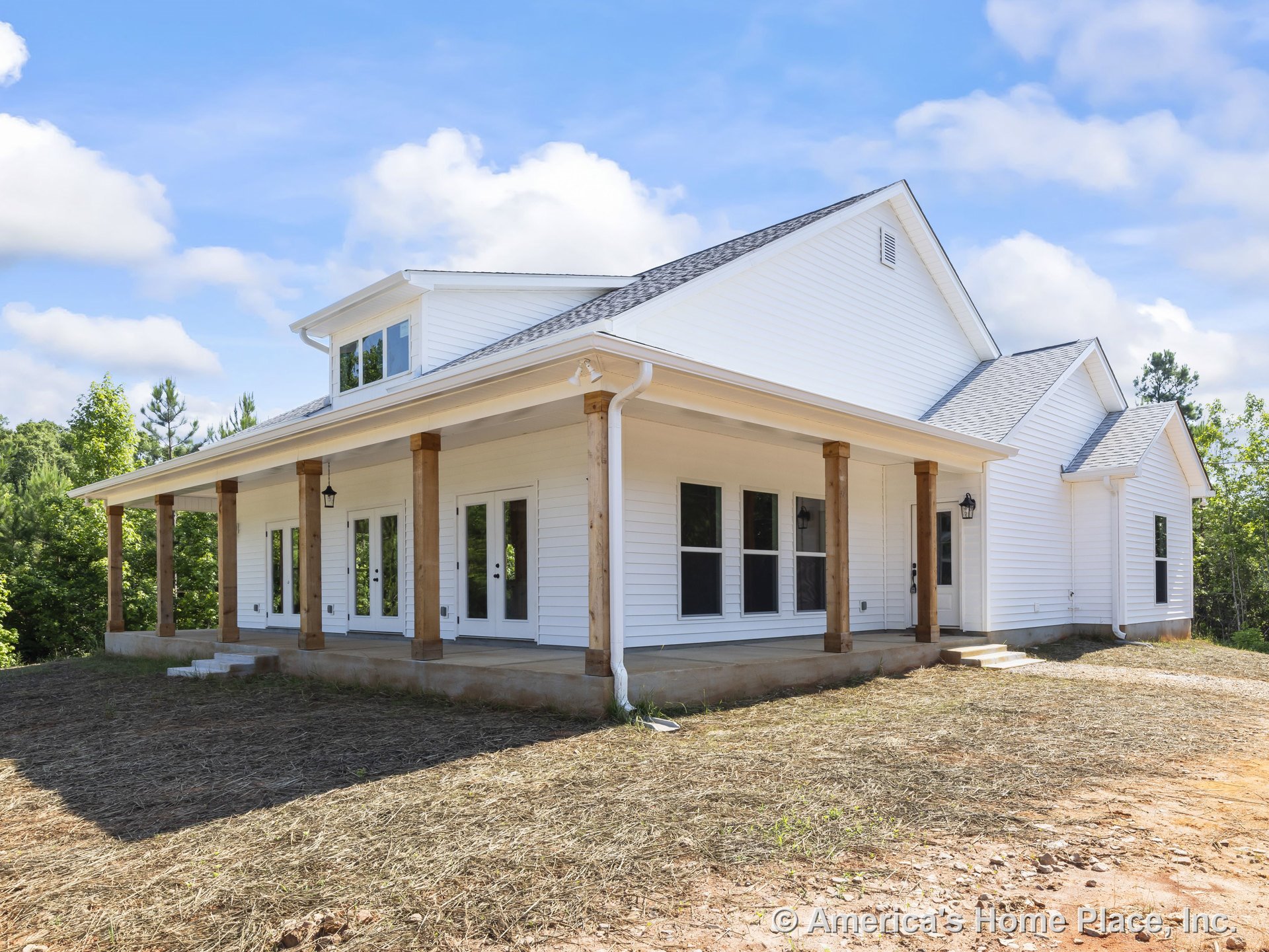 Large covered front porch with white horizontal siding, wooden columns, multiple glass exterior doors, black lantern lighting fixtures, architectural roof gables, and detailed trim