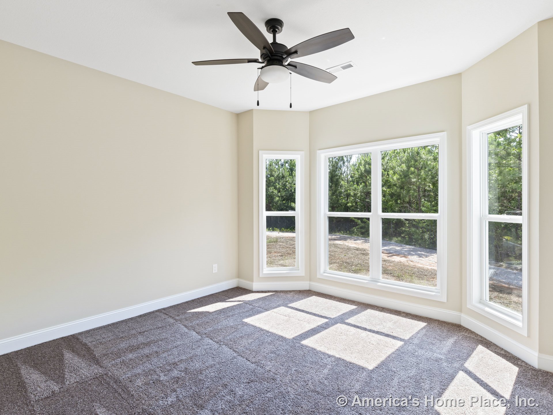 Bedroom with three-panel bay window, neutral beige walls, white baseboard trim, carpet flooring, ceiling fan with built-in light, and abundant natural light from large windows.