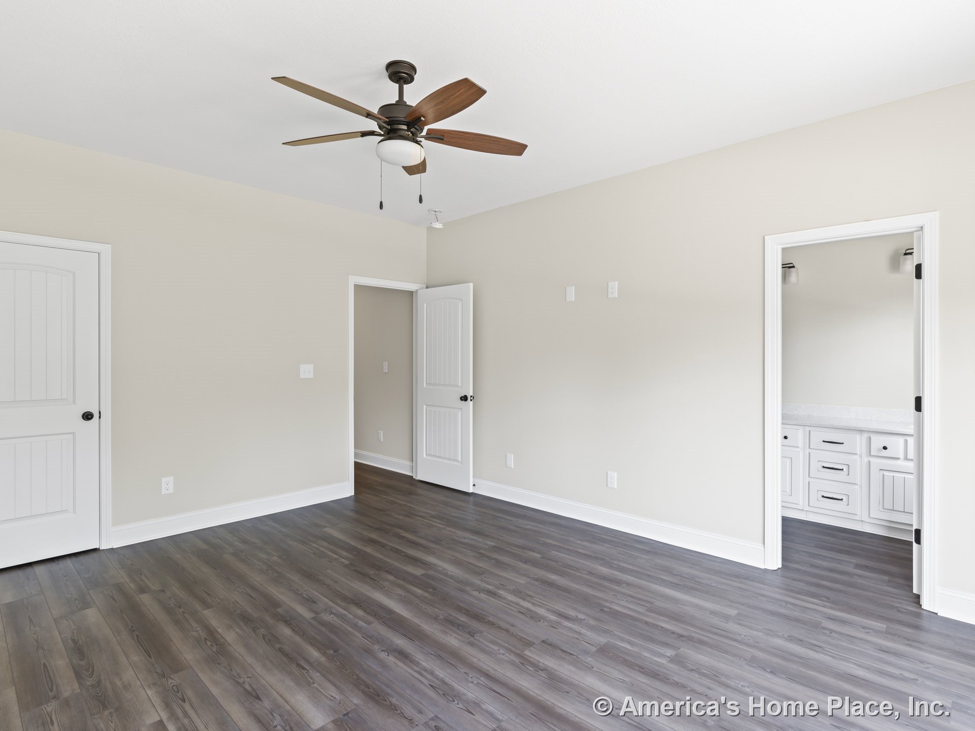 Bedroom with wood-look plank flooring, ceiling fan and light fixture, white baseboards, paneled interior doors, neutral wall paint, and en suite bathroom featuring a vanity with