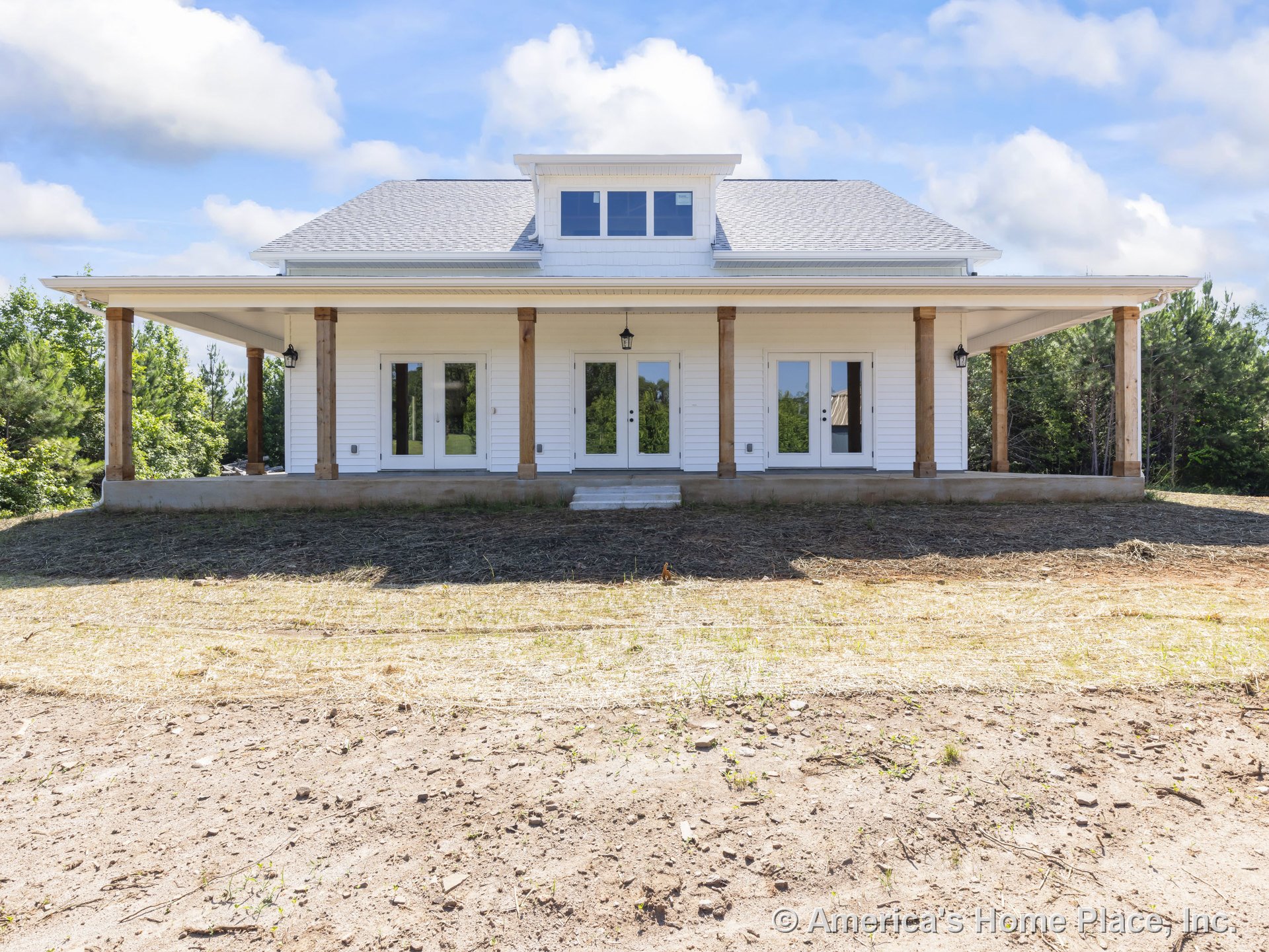Large covered front porch with wood support columns, multiple exterior glass doors, white horizontal siding, lantern-style porch lighting, hip roof with dormer window, and detailed