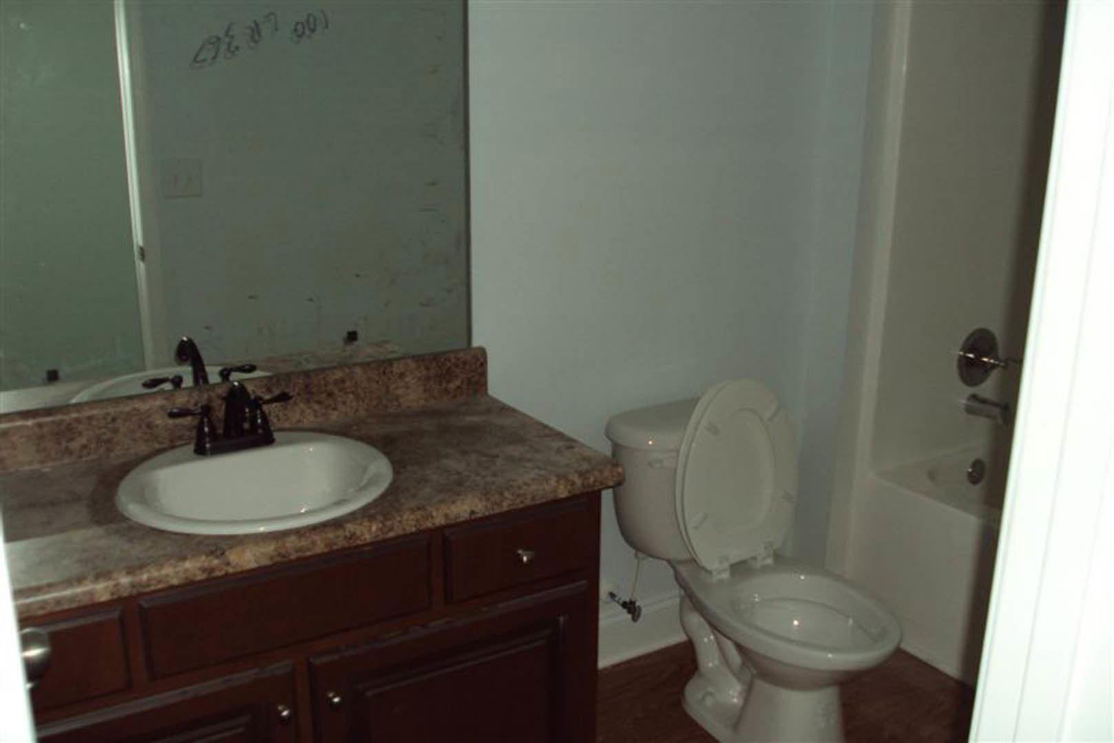 White porcelain sink with chrome faucet beside a toilet with lid up, light gray tile flooring, white cabinetry, and neutral painted walls