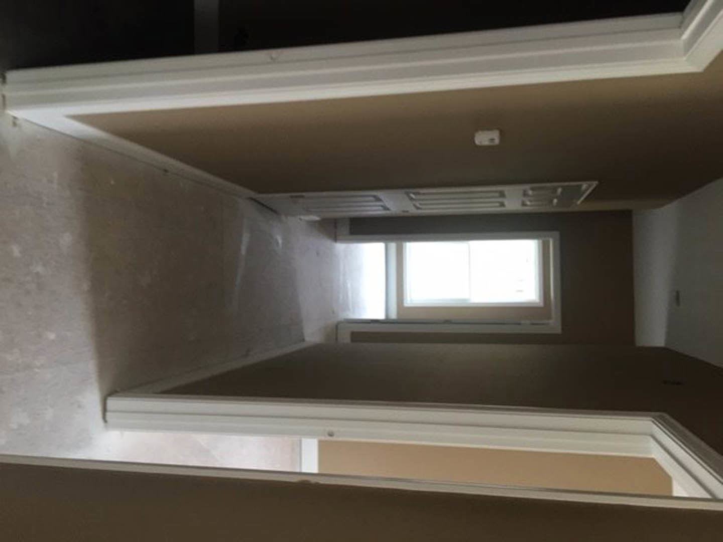 Bright hallway with plaster walls, white ceiling molding, wood floor, and large window providing natural daylight.