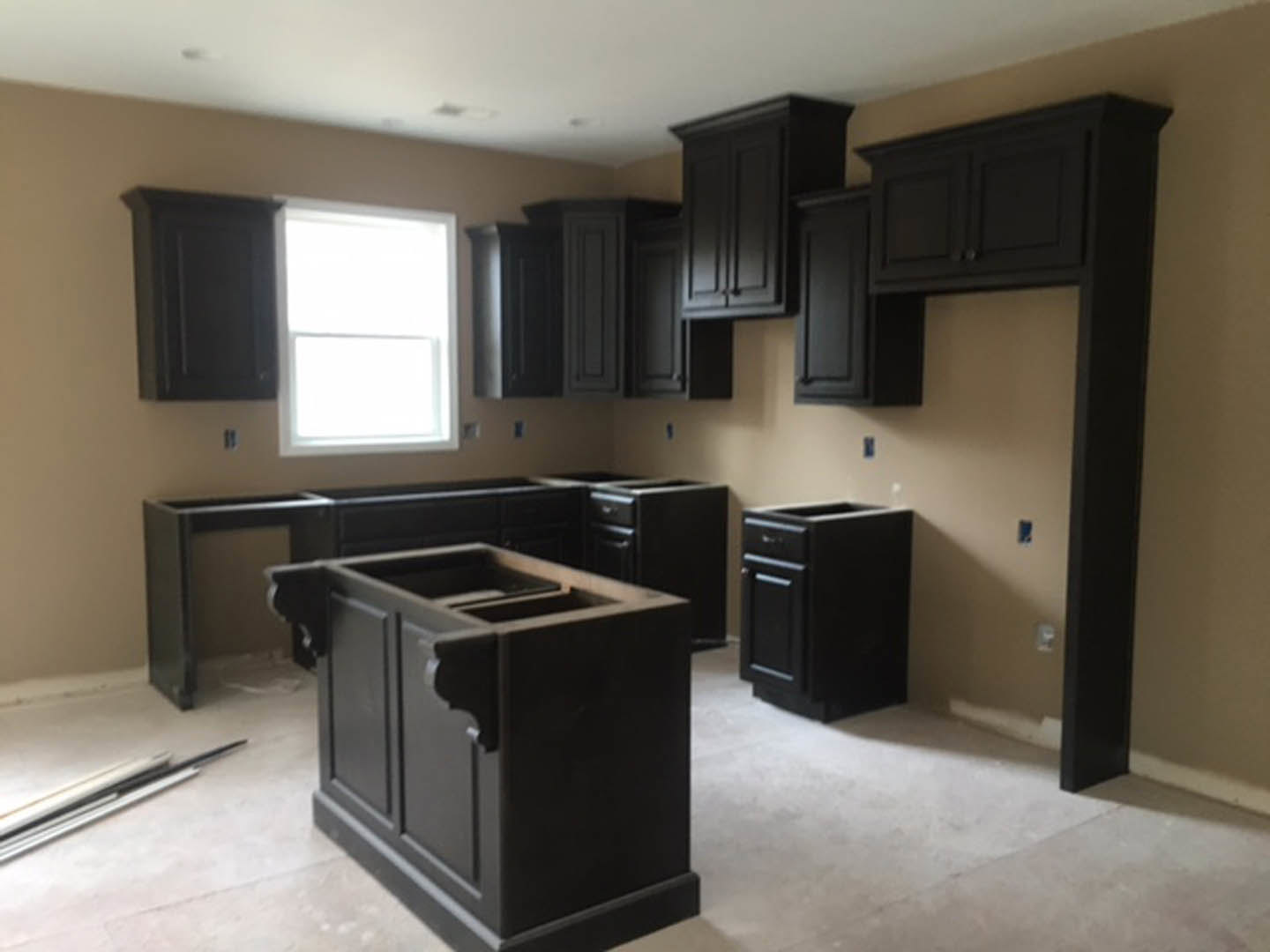Black kitchen cabinets with matte finish, white quartz countertops, stainless steel appliances, and a window with a white frame letting in natural light.