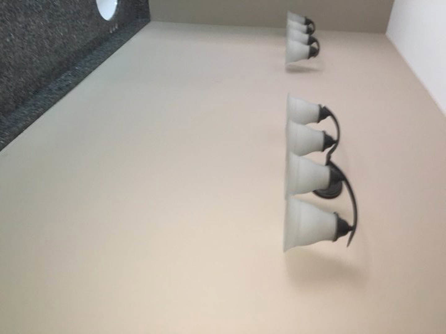 Row of modern white light fixtures mounted on a smooth white interior wall above light-colored flooring