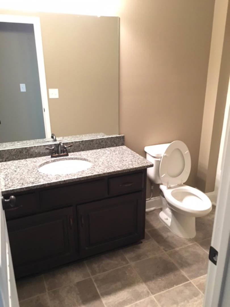 Modern bathroom with white porcelain sink and toilet, chrome faucet, light-colored tile floor, and neutral painted walls