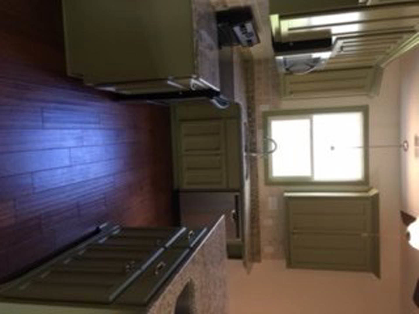 Modern kitchen featuring stainless steel refrigerator, undermount sink set in quartz countertop, white shaker cabinetry, and light wood flooring