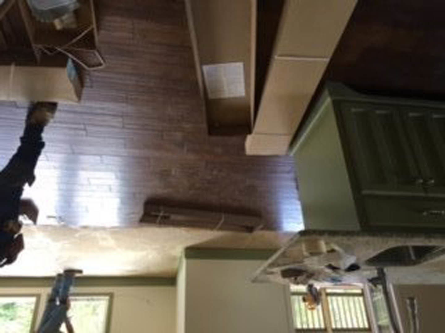 Open kitchen with light wood cabinetry, stone countertops, stainless steel appliances, and two dining tables on hardwood flooring