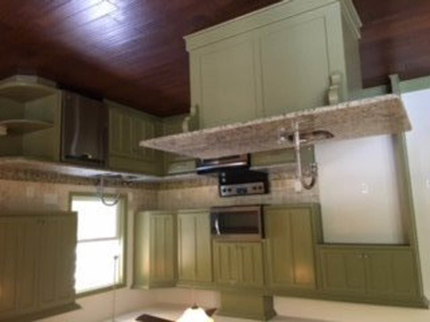 Kitchen with matte green cabinets, stainless steel stove, white countertops, and a range hood
