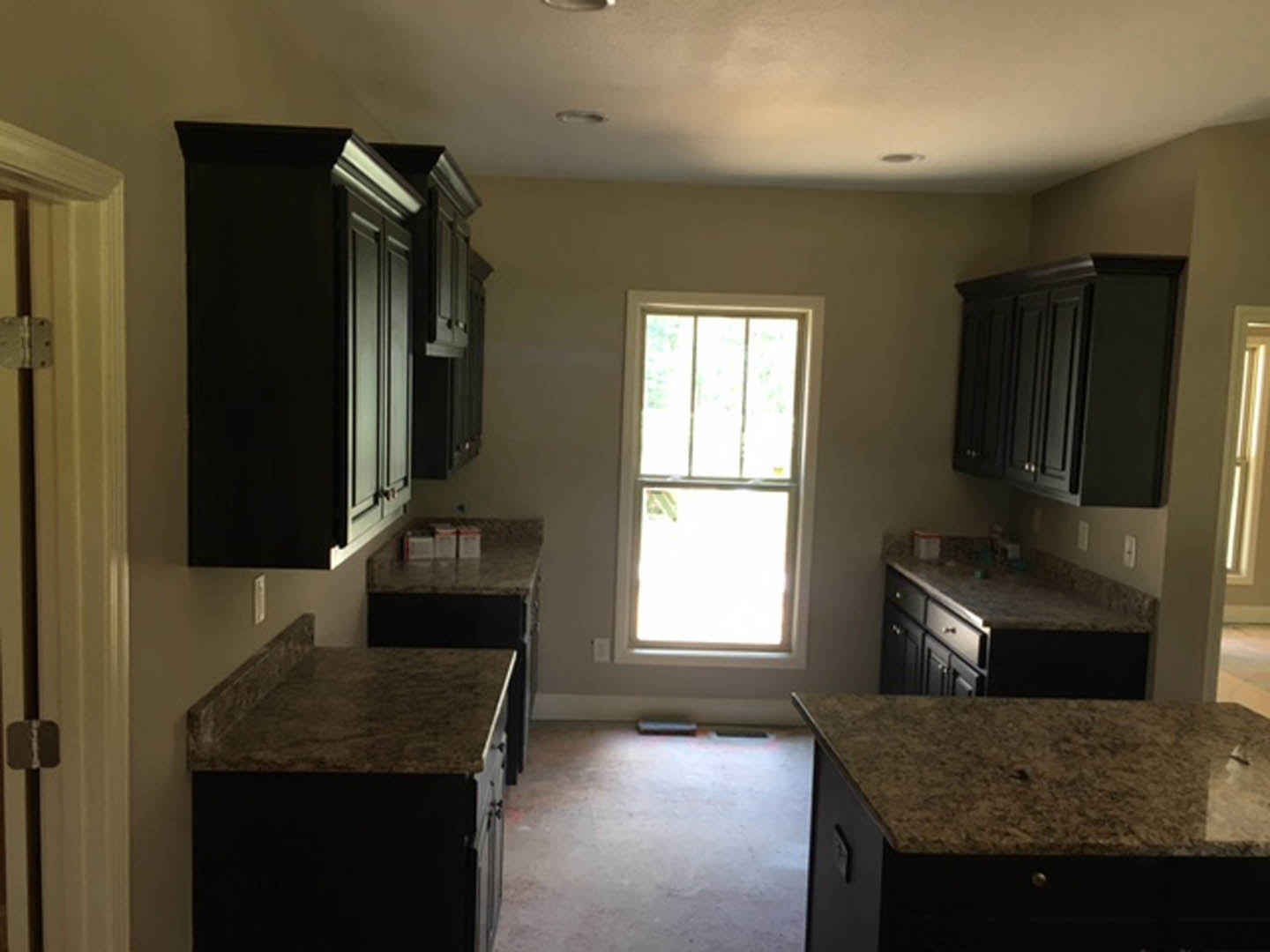 Granite countertops with undermount sink, black cabinetry, window letting in natural light, close-up of drawer and door hinge, white walls and ceiling