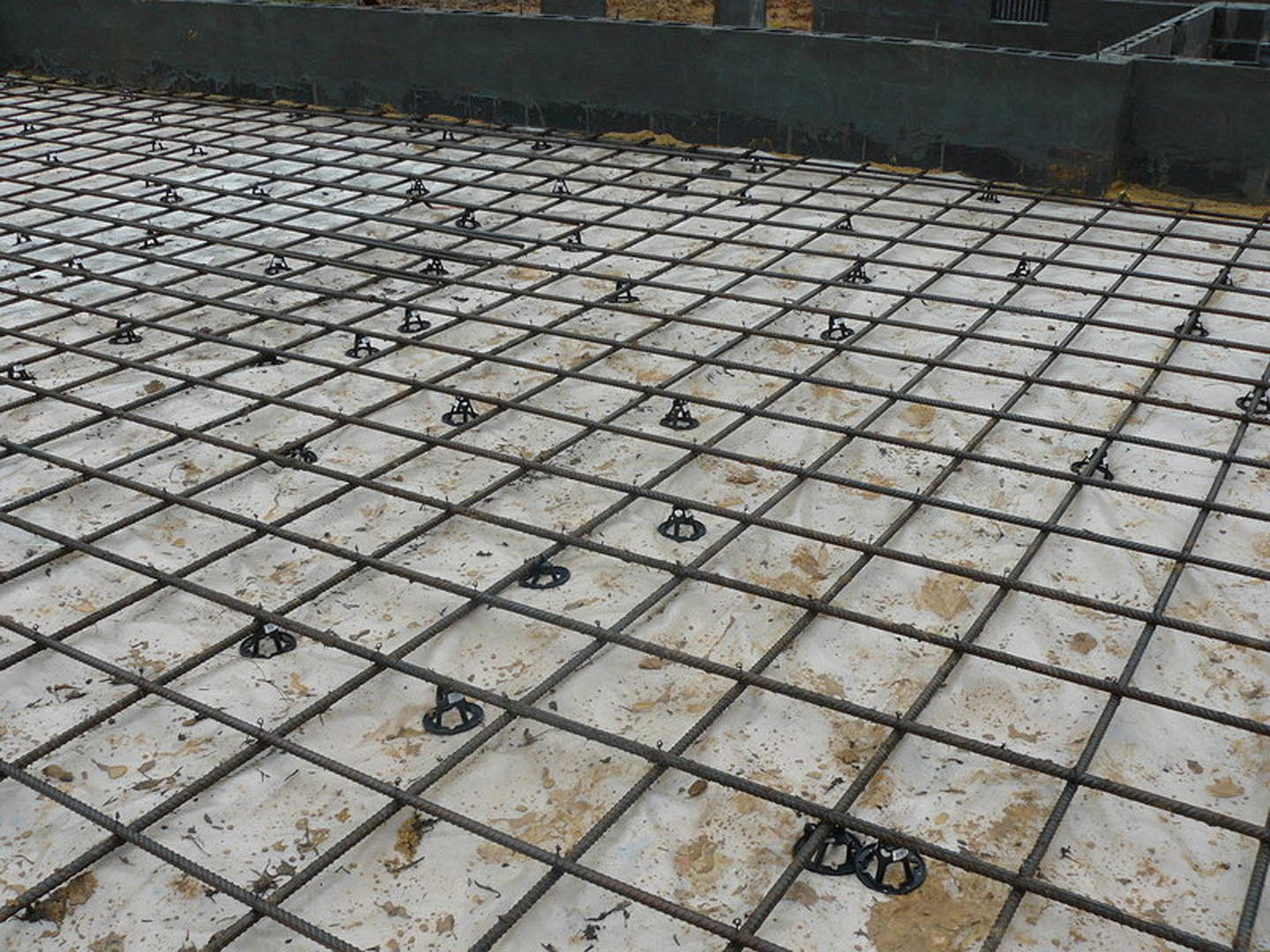 Steel rebar grid embedded in smooth concrete floor with flagstone texture