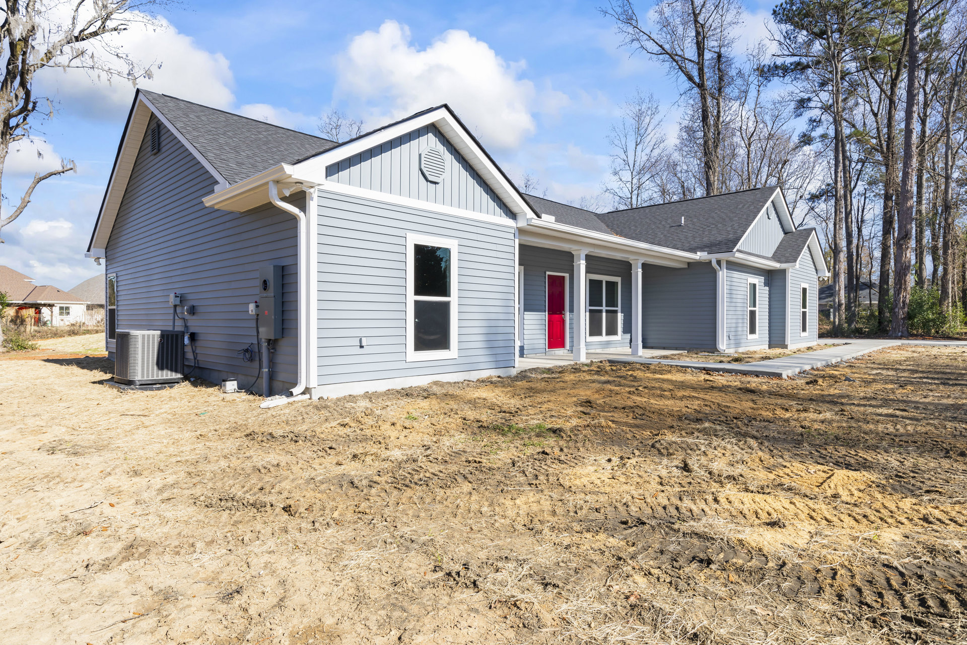 Two-story home with white siding, red front door, and large windows, set on a grassy yard under a blue sky; Robert Frost Farm visible in the background.