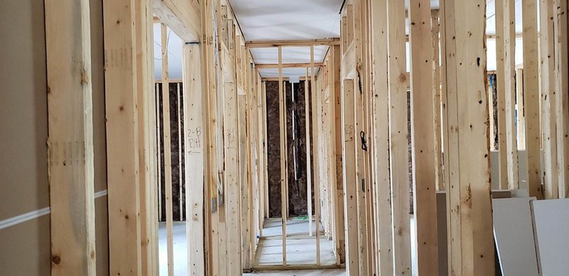 Wood-framed room with exposed beams, white wall featuring a grey horizontal stripe, metal bar integrated into framing, close-up views of window frame and white rectangular object