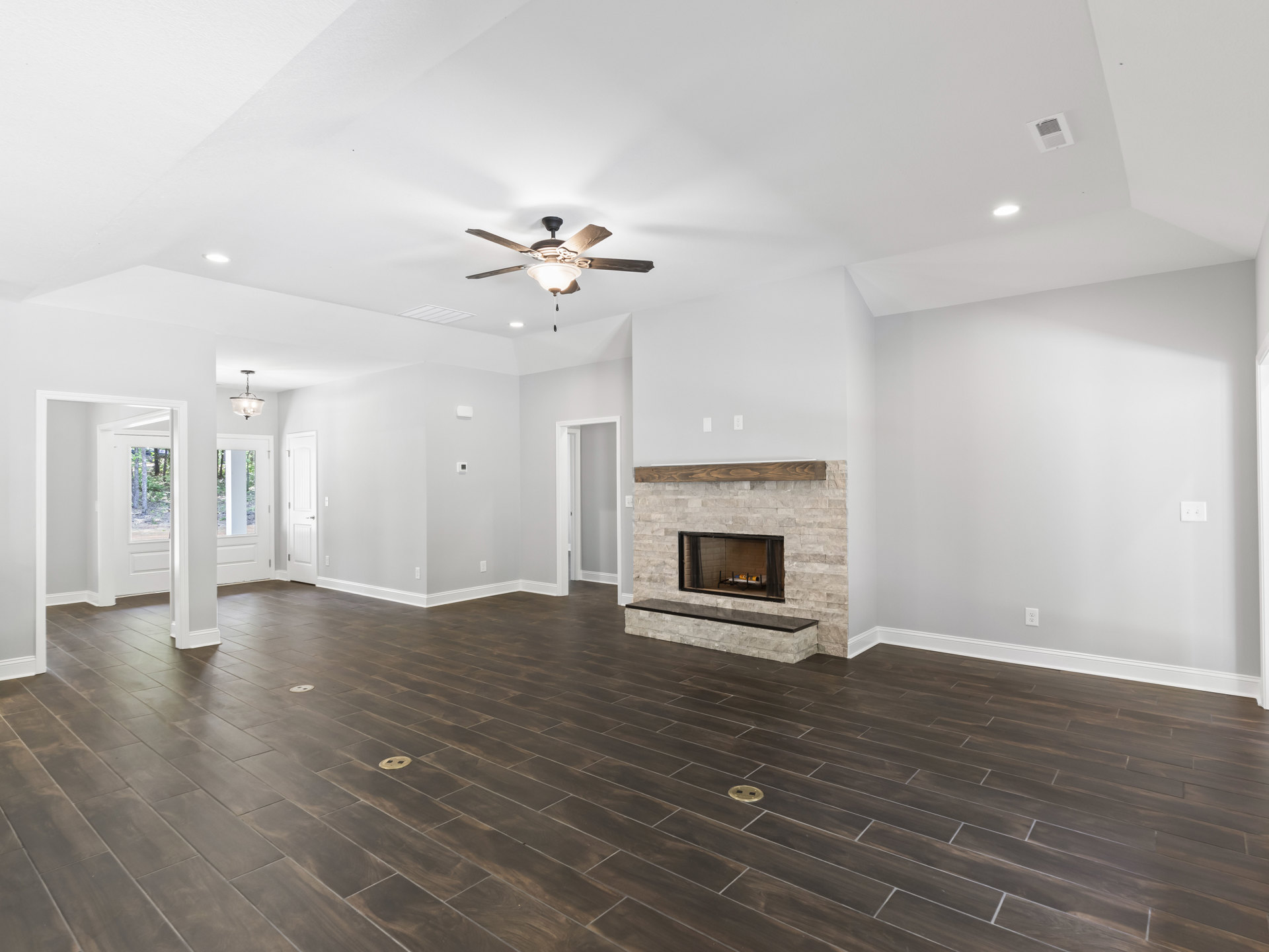 Hardwood flooring, white plaster walls, ceiling fan with light fixture, glass-door fireplace with metal screen, ceiling vent