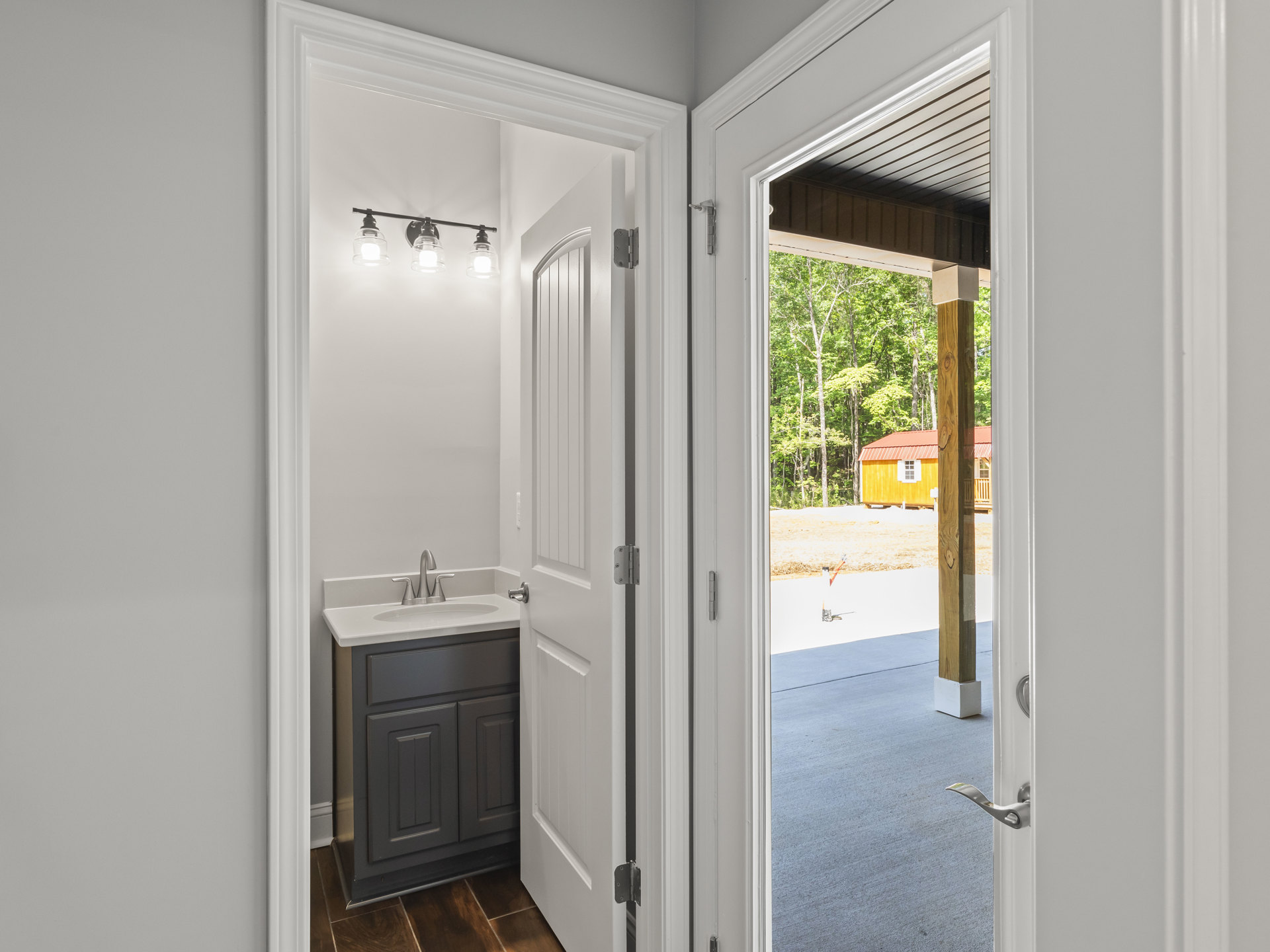 Bathroom with white sink set in wood vanity, wood plank flooring, wall-mounted mirror, and neutral tile walls