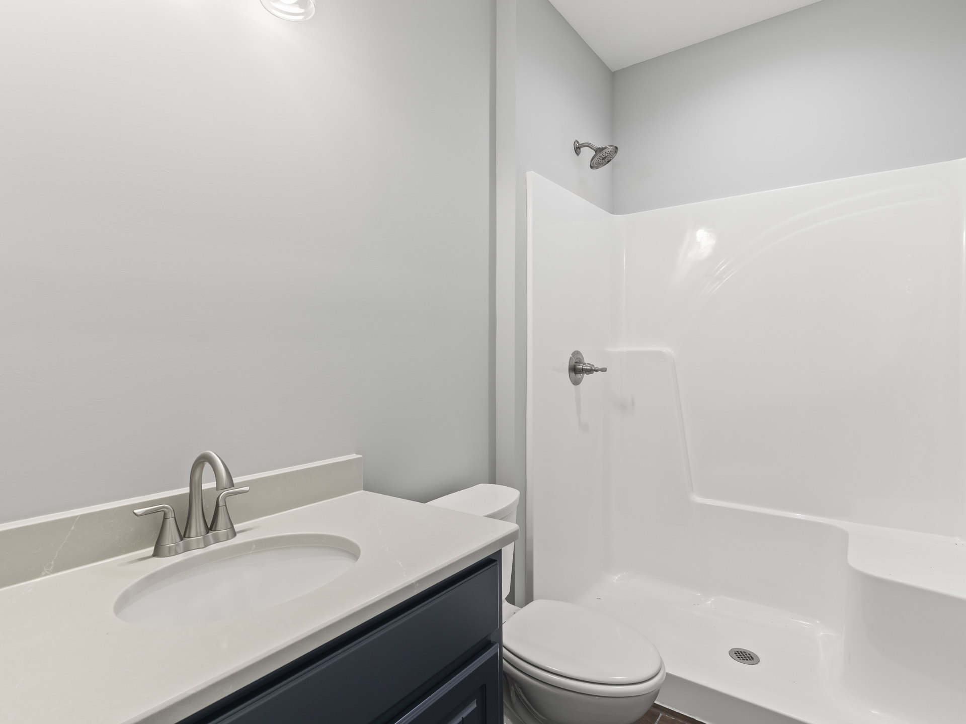 Modern bathroom with white tile walls, built-in shower with round showerhead, closed toilet, and rectangular sink with chrome faucet