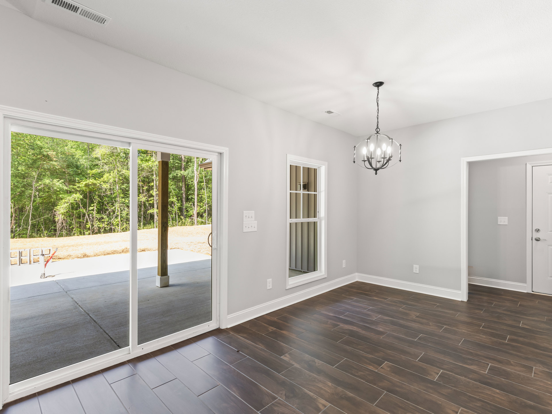 Wood floor room featuring a sliding glass door, white-framed window, ceiling chandelier, and red barrier tape near the entrance.