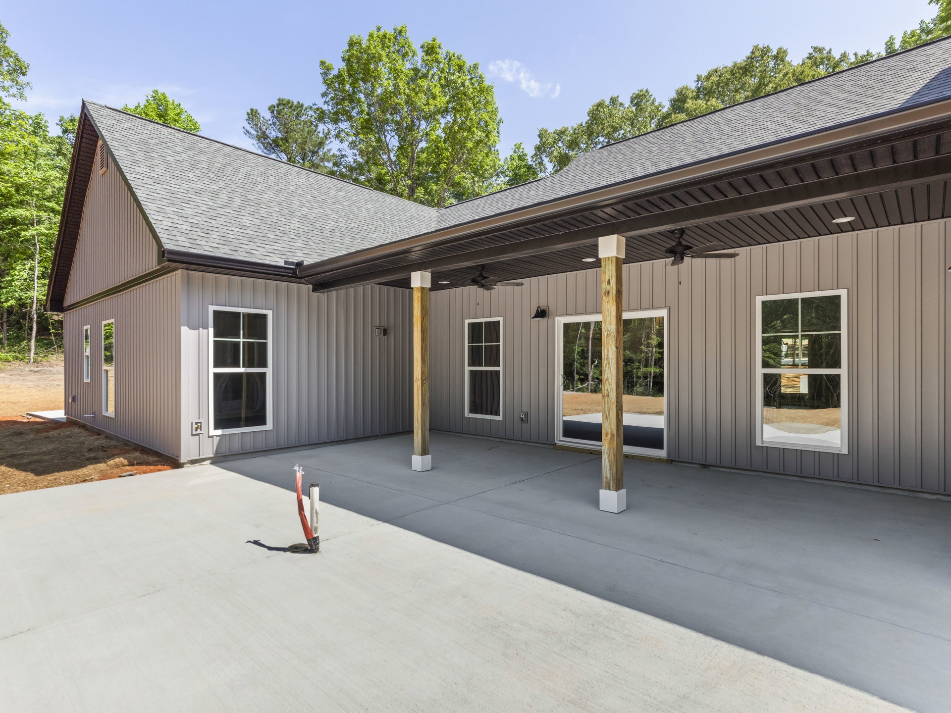 Front porch with white-framed windows, gabled roof, and surrounding trees; reflection of car and greenery visible in glass