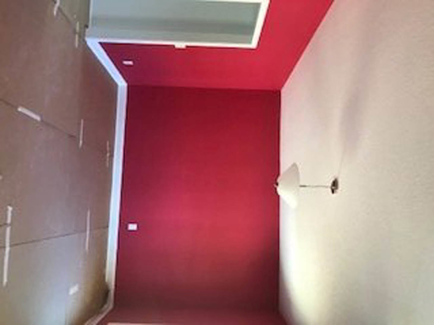 Red plaster bathroom wall with white square fixture and white ceiling.