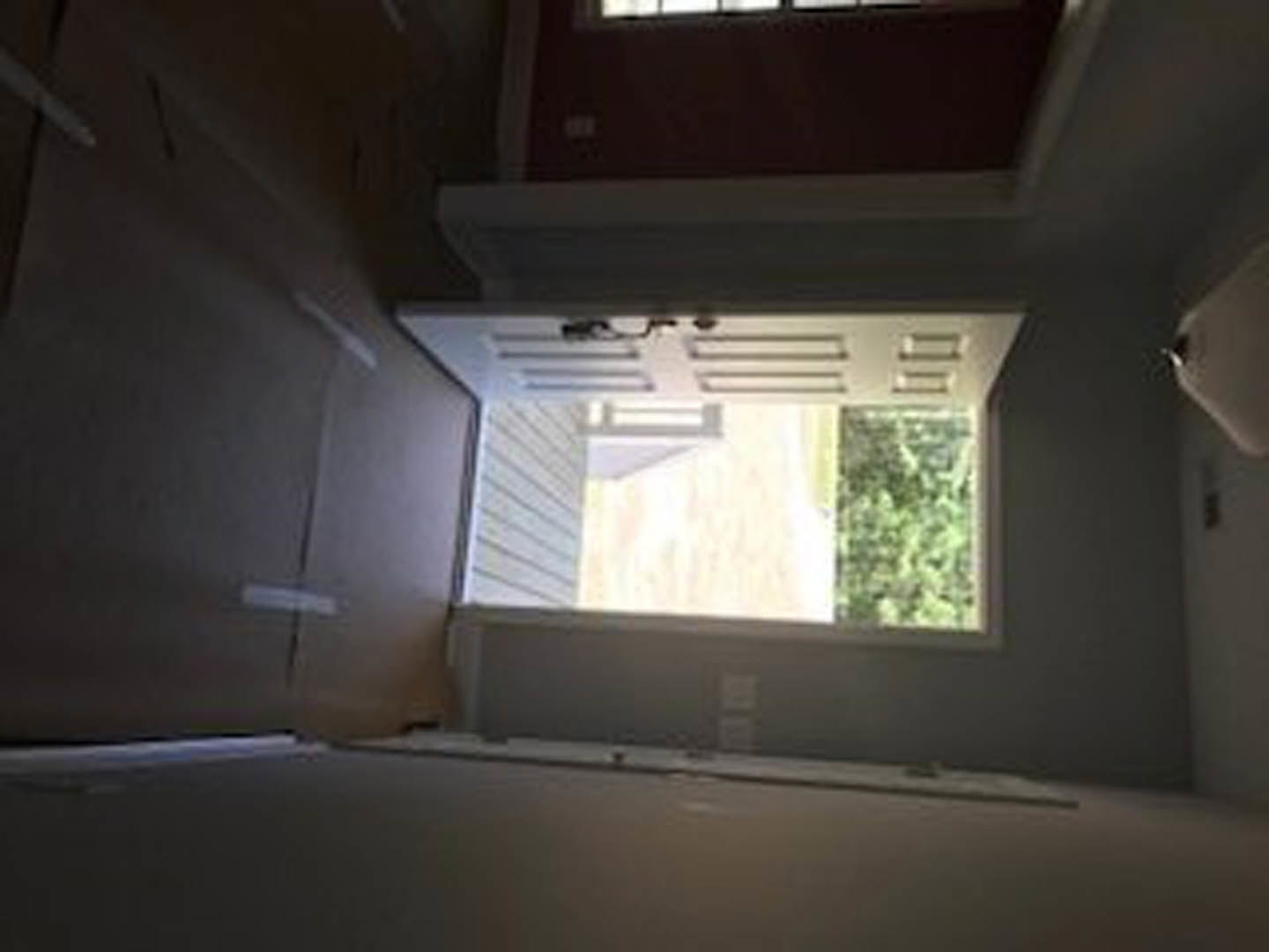White paneled door with silver handle set in a light gray brick wall, sunlight streaming through nearby window, neutral-toned interior visible beyond doorway
