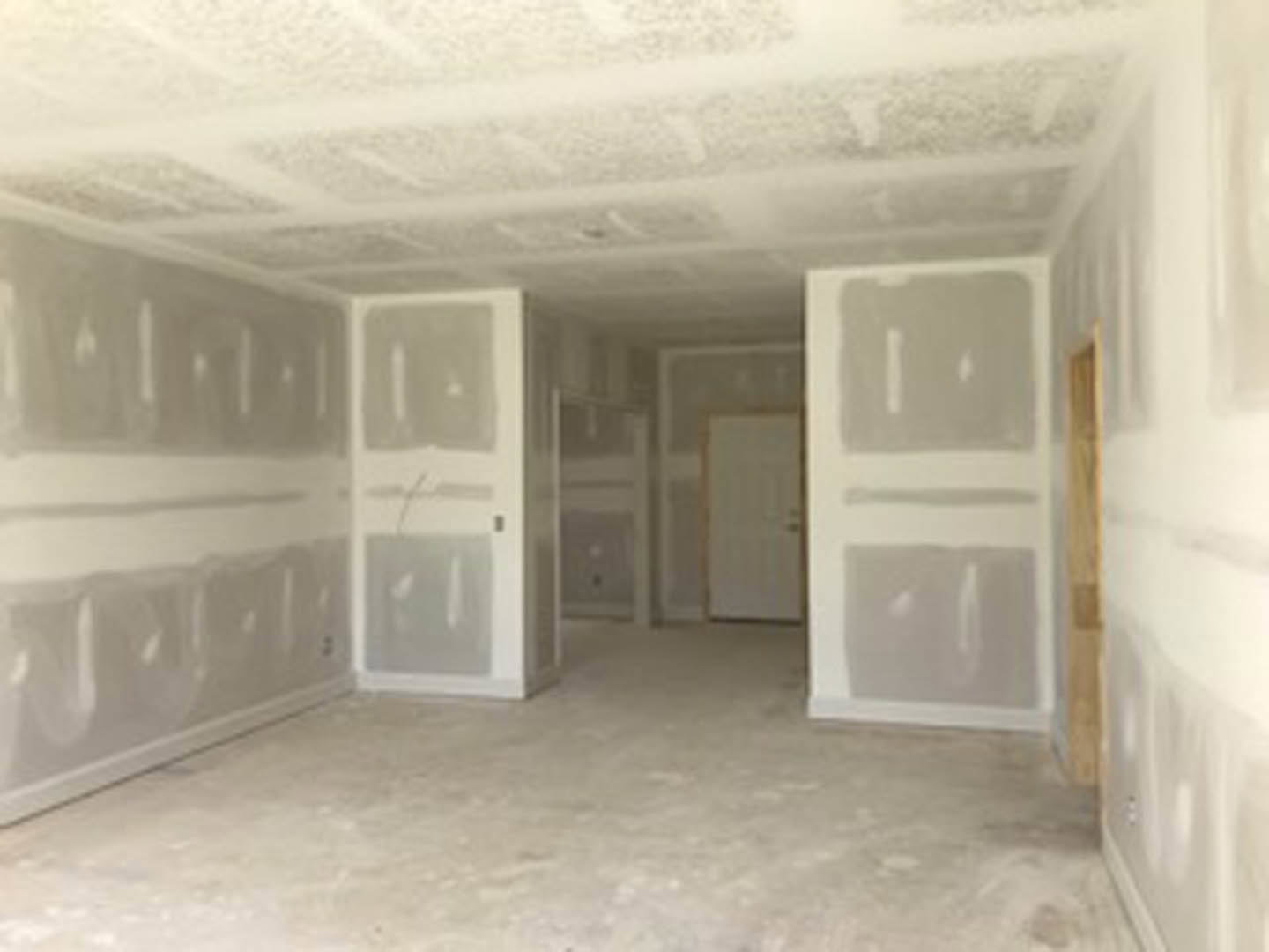 White plaster walls, white door with gold handle, light wood floor, ceiling, and window in a residential room