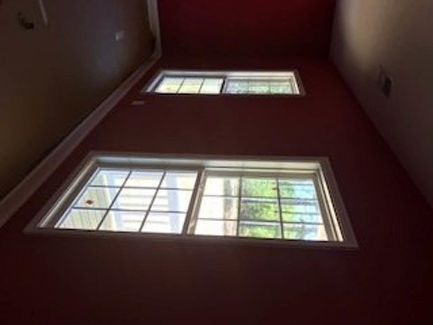 Light-filled room with two rectangular windows, white walls, and smooth ceiling, natural daylight streaming in