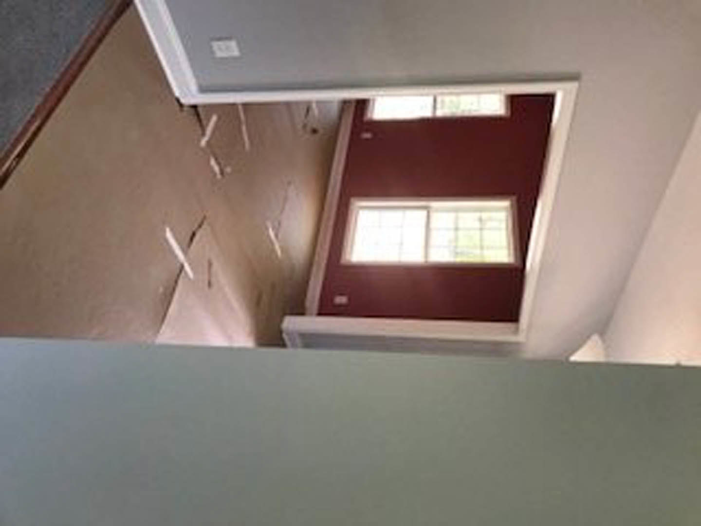 Red accent wall with white trim and windows, adjacent to white walls, ceiling, and wood-edged surfaces in a residential interior.