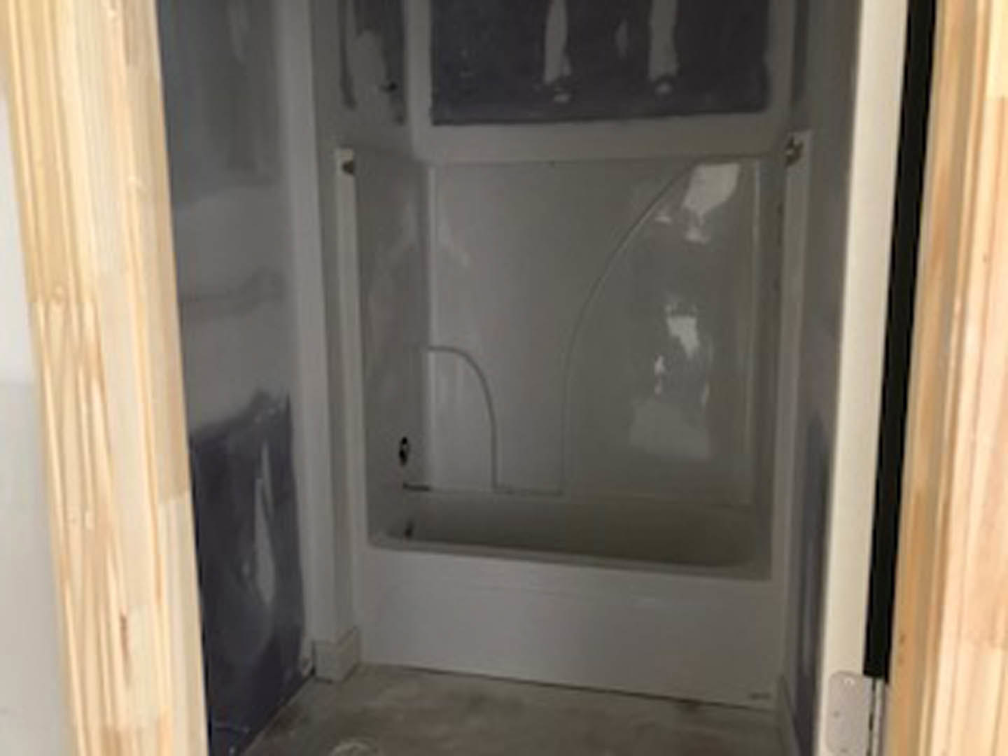 Modern bathroom featuring a freestanding soaking tub, glass-enclosed shower with tile walls, plaster finishes, and a sleek door with a metal handle