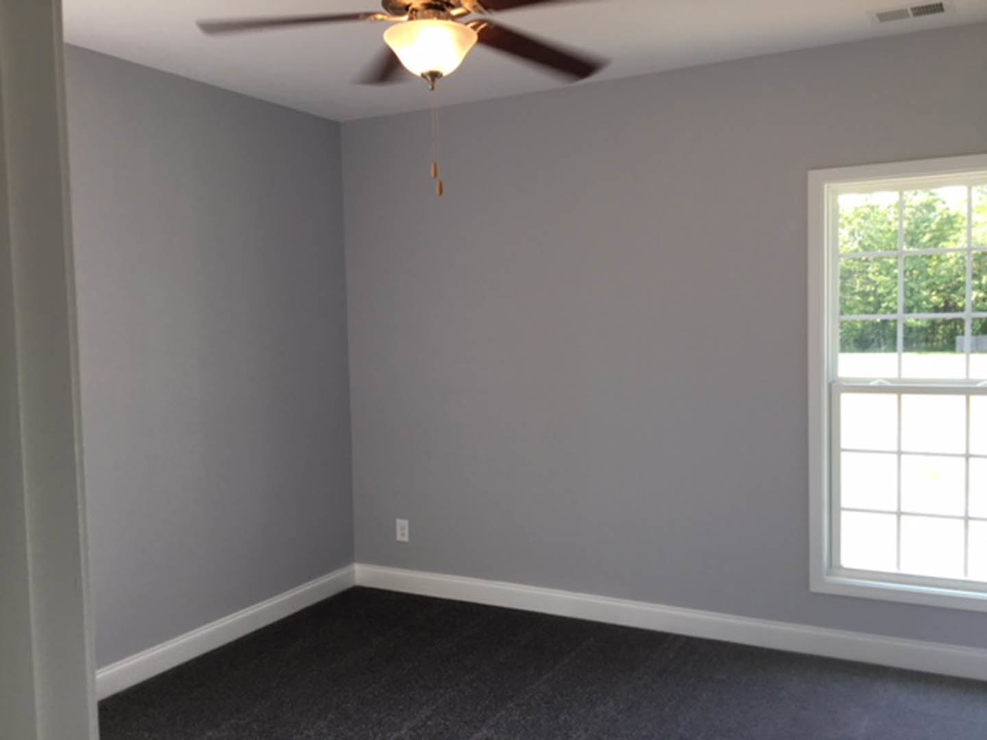 Bedroom with grey carpet, white walls, multi-pane window, and modern ceiling fan with brushed metal finish