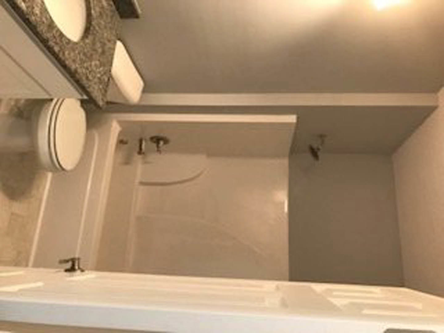 Modern bathroom featuring a glass-enclosed shower, white ceramic sink with chrome faucet, large wall mirror, and light gray tile walls.