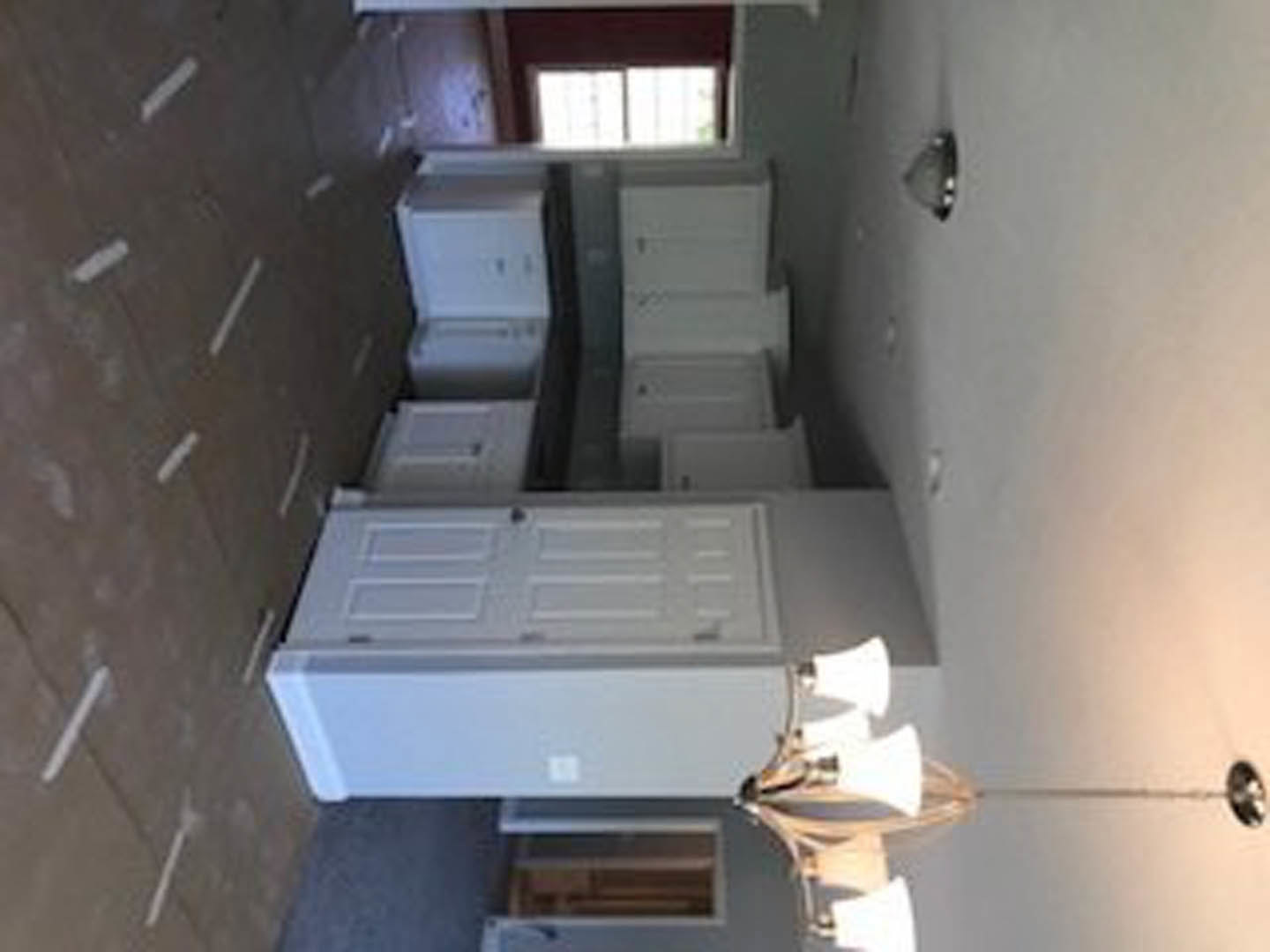 White shaker cabinets with brushed nickel hardware, pendant light fixture, and neutral painted walls in a modern kitchen.