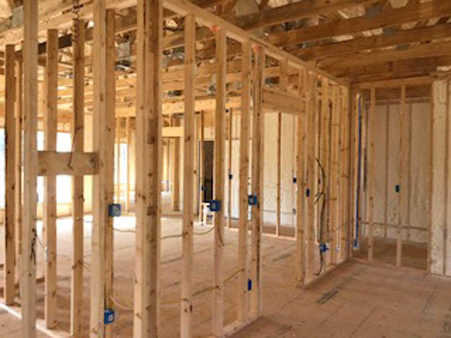 Exposed wooden beams and framing inside a partially constructed house with unfinished ceiling and floor