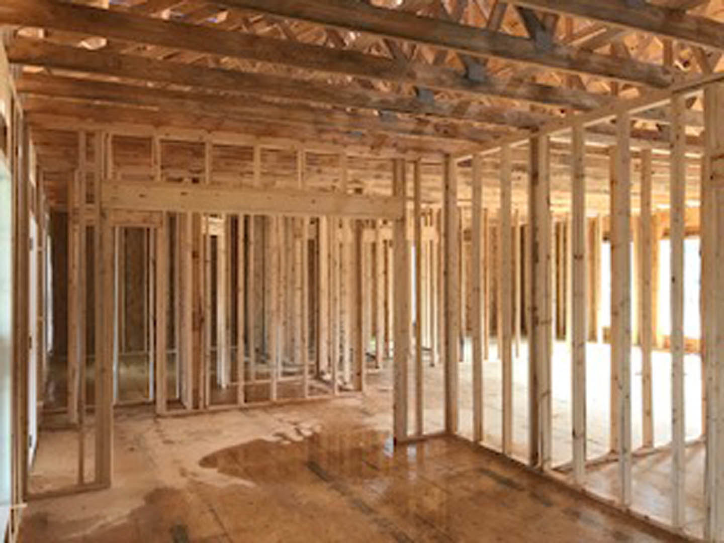 Open living space featuring exposed wood ceiling beams, hardwood flooring, large window, and neutral walls.