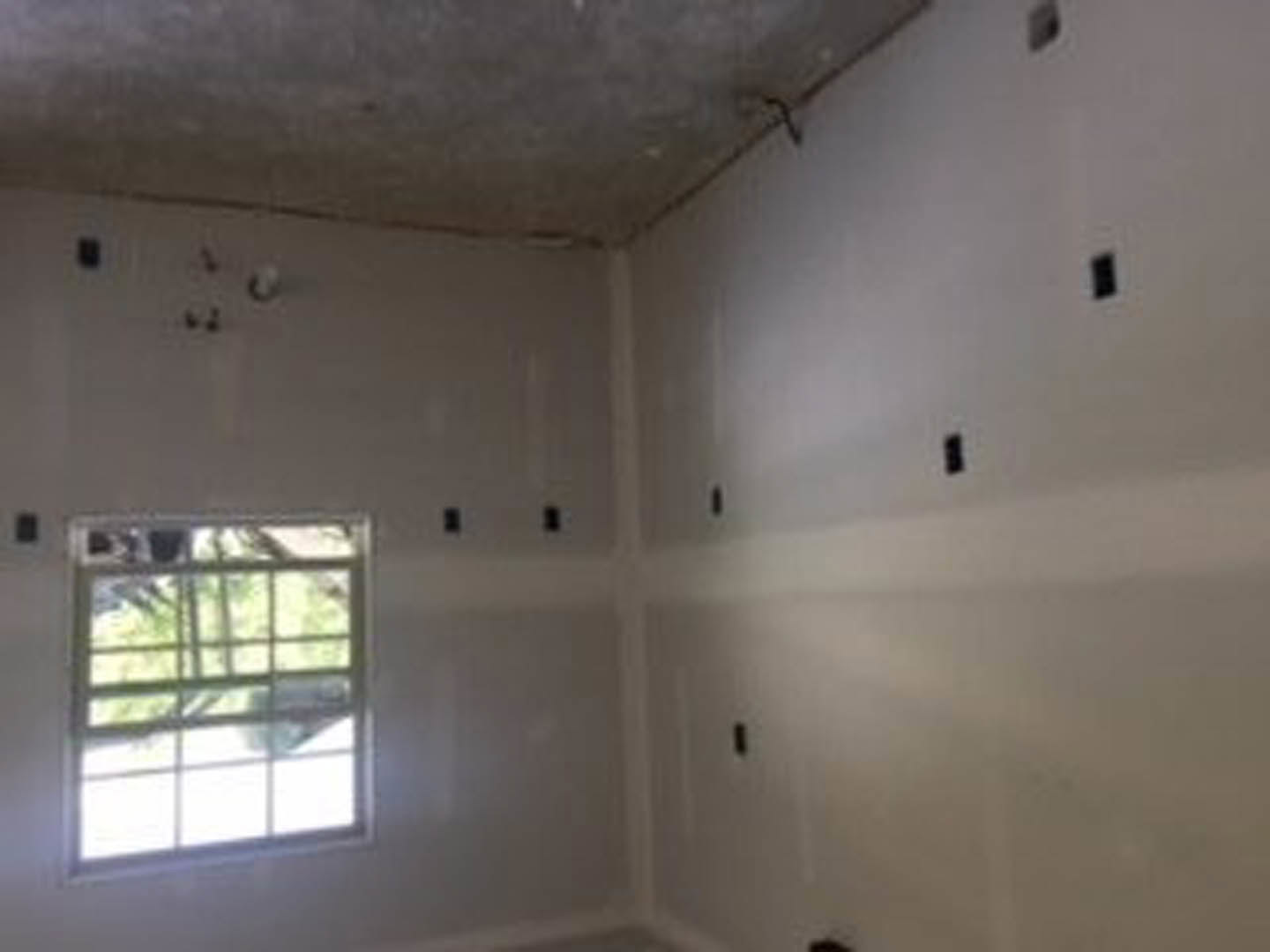 Bright room with two large windows, white plaster walls, smooth grey surface, and ceiling fixture.