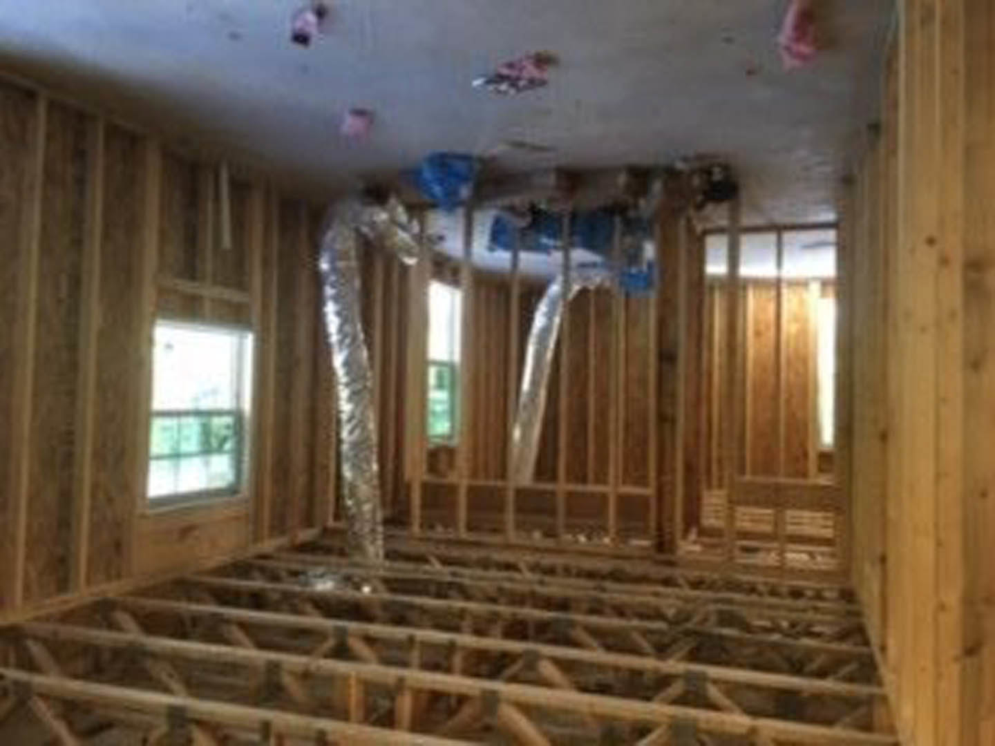 Living room with exposed wood ceiling beams, white walls, large window, and natural wood finishes