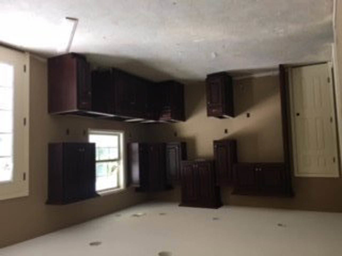 Light-filled room featuring white cabinetry, multiple windows with trim, white door with black hardware, smooth plaster walls, and ceiling.