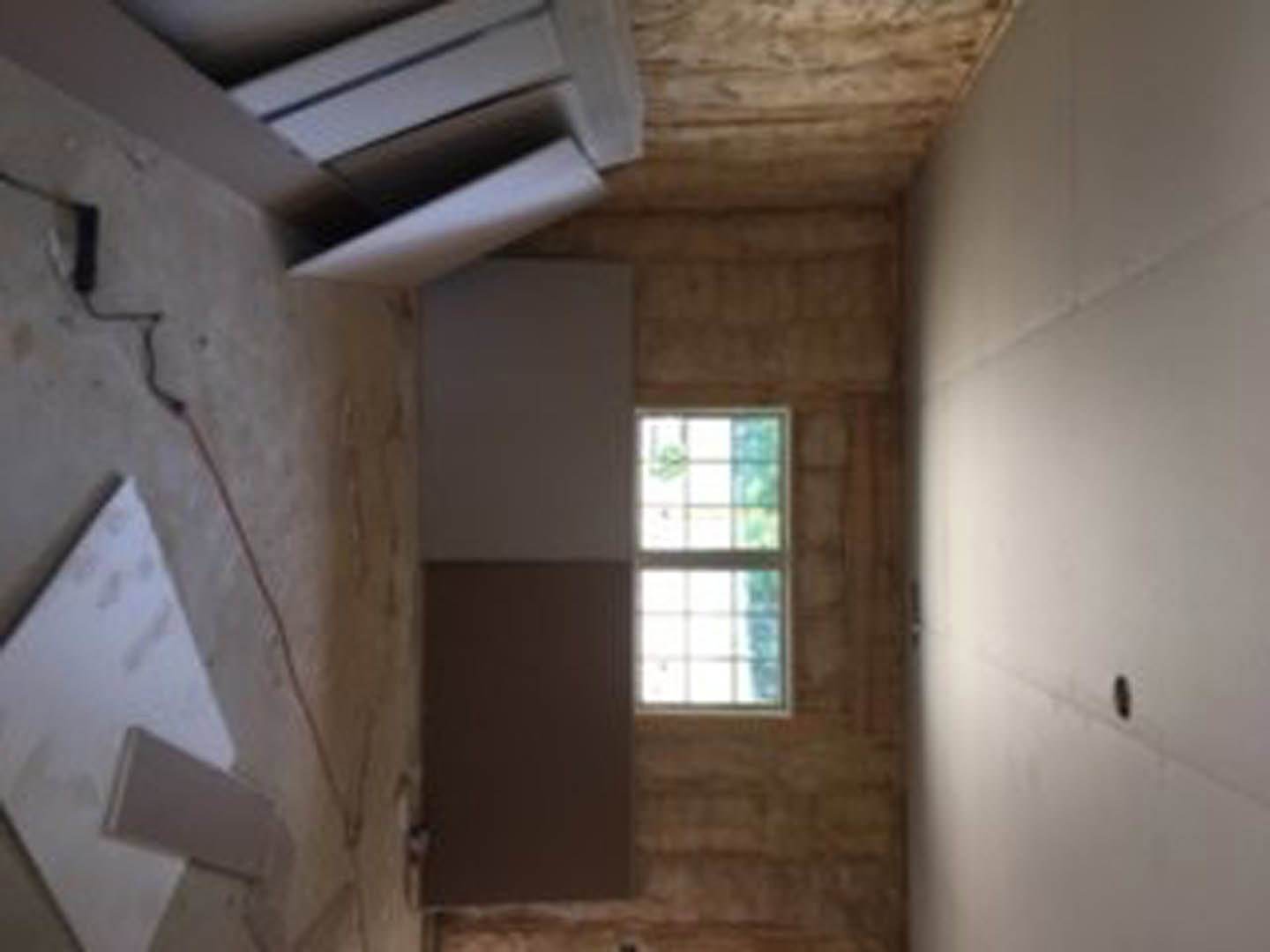 Sunlit room with plaster walls, large window, light wood floor, and white ceiling