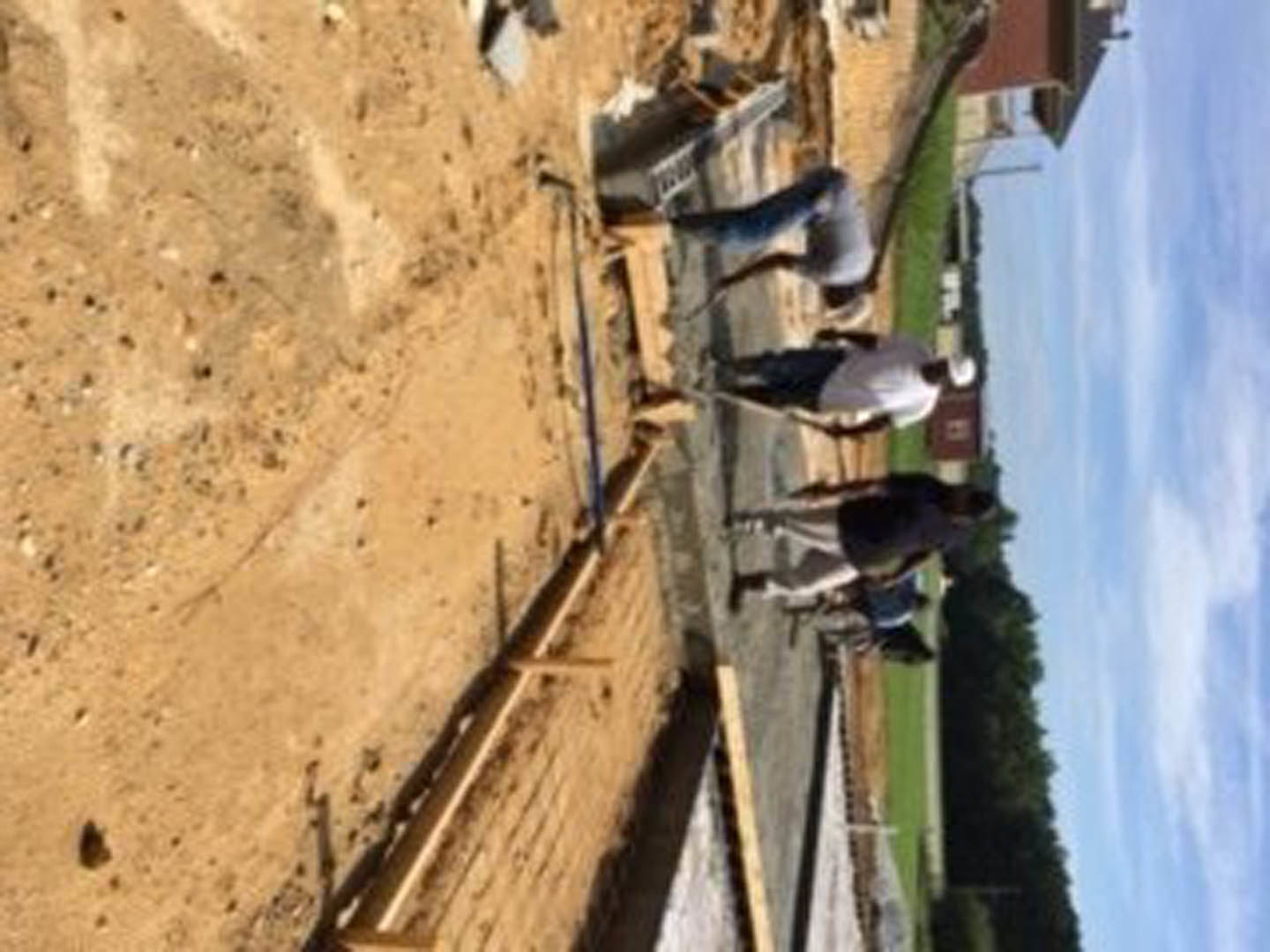 Workers assembling framing and exterior walls on a residential construction site under partly cloudy sky