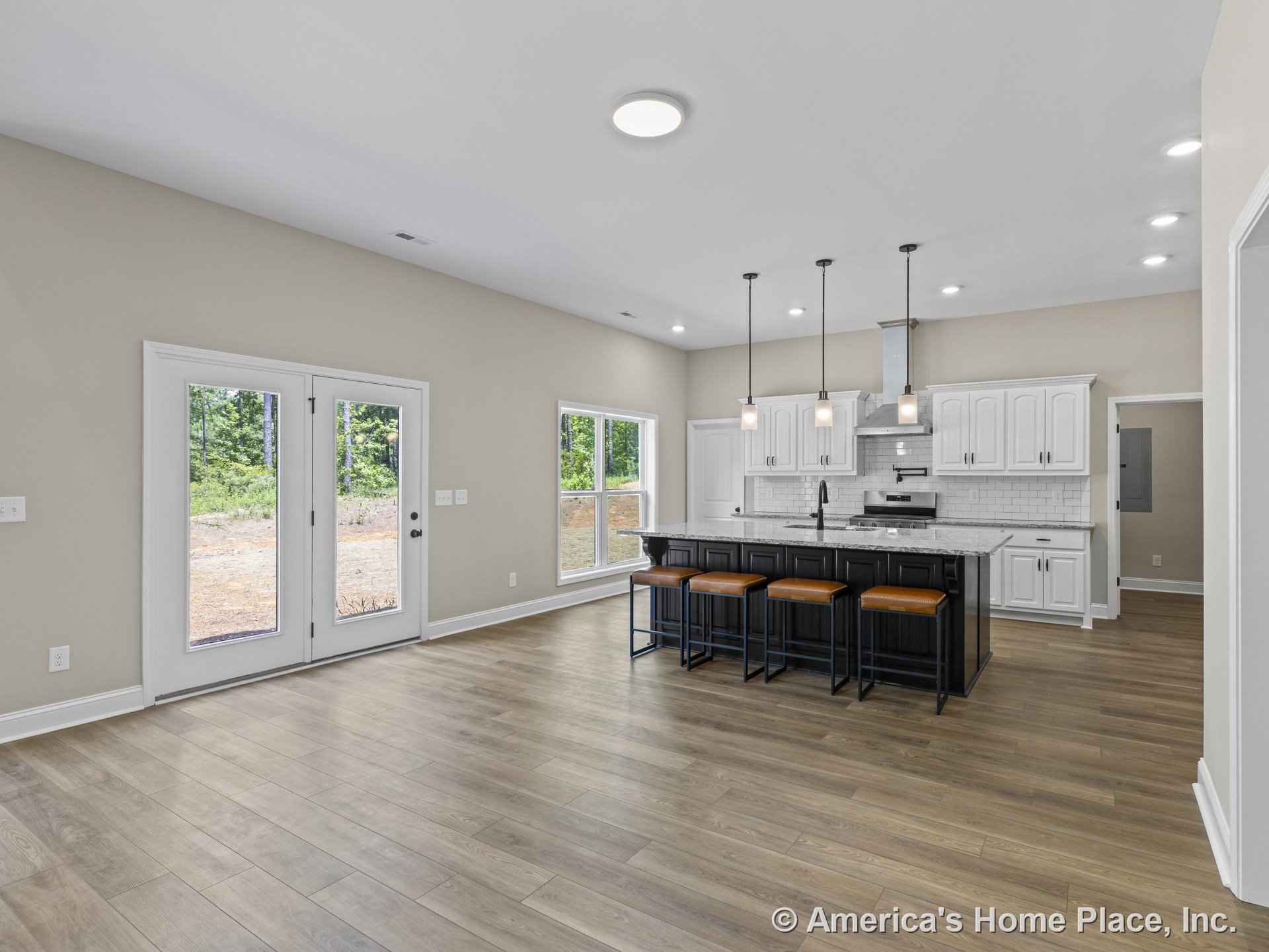 Open kitchen with white cabinetry, black island topped with stone countertops, wide plank wood flooring, white subway tile backsplash, pendant and recessed ceiling lights, double