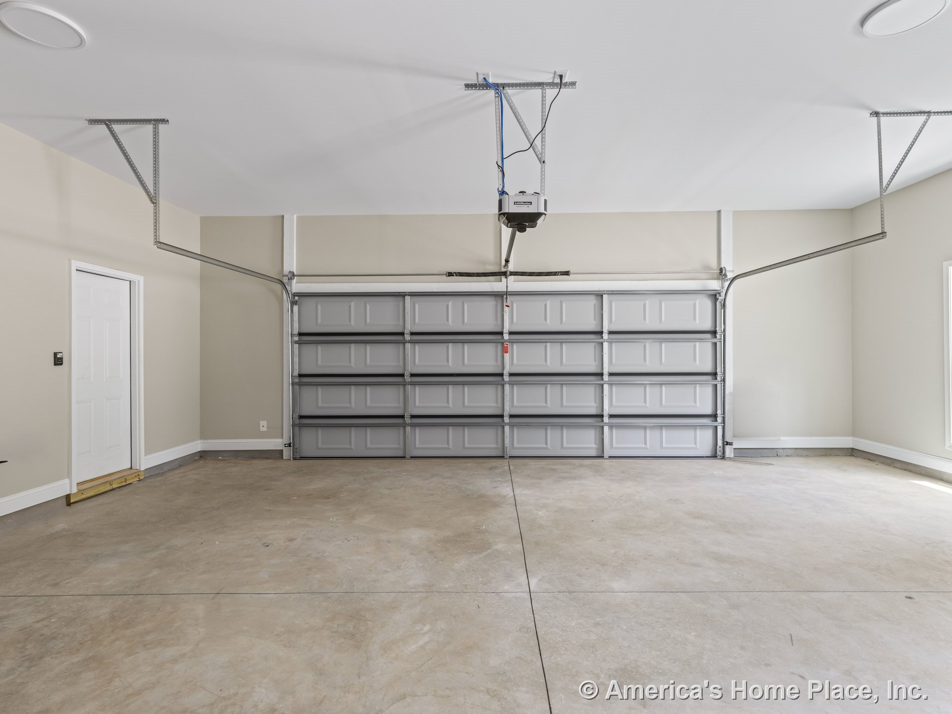 Double bay overhead garage door with automatic opener, unfinished concrete floor, beige painted walls with white trim, side entry door, ceiling lighting, and window.