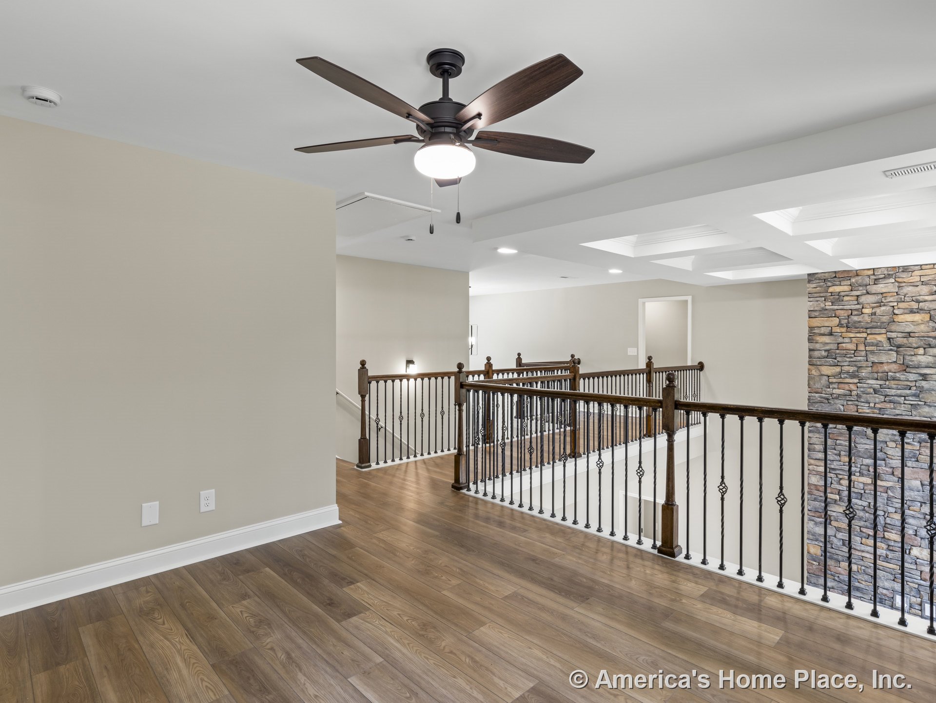Upstairs landing with wood plank flooring, iron baluster staircase, stone accent wall, coffered ceiling, ceiling fan with light, recessed lighting, and neutral wall color.
