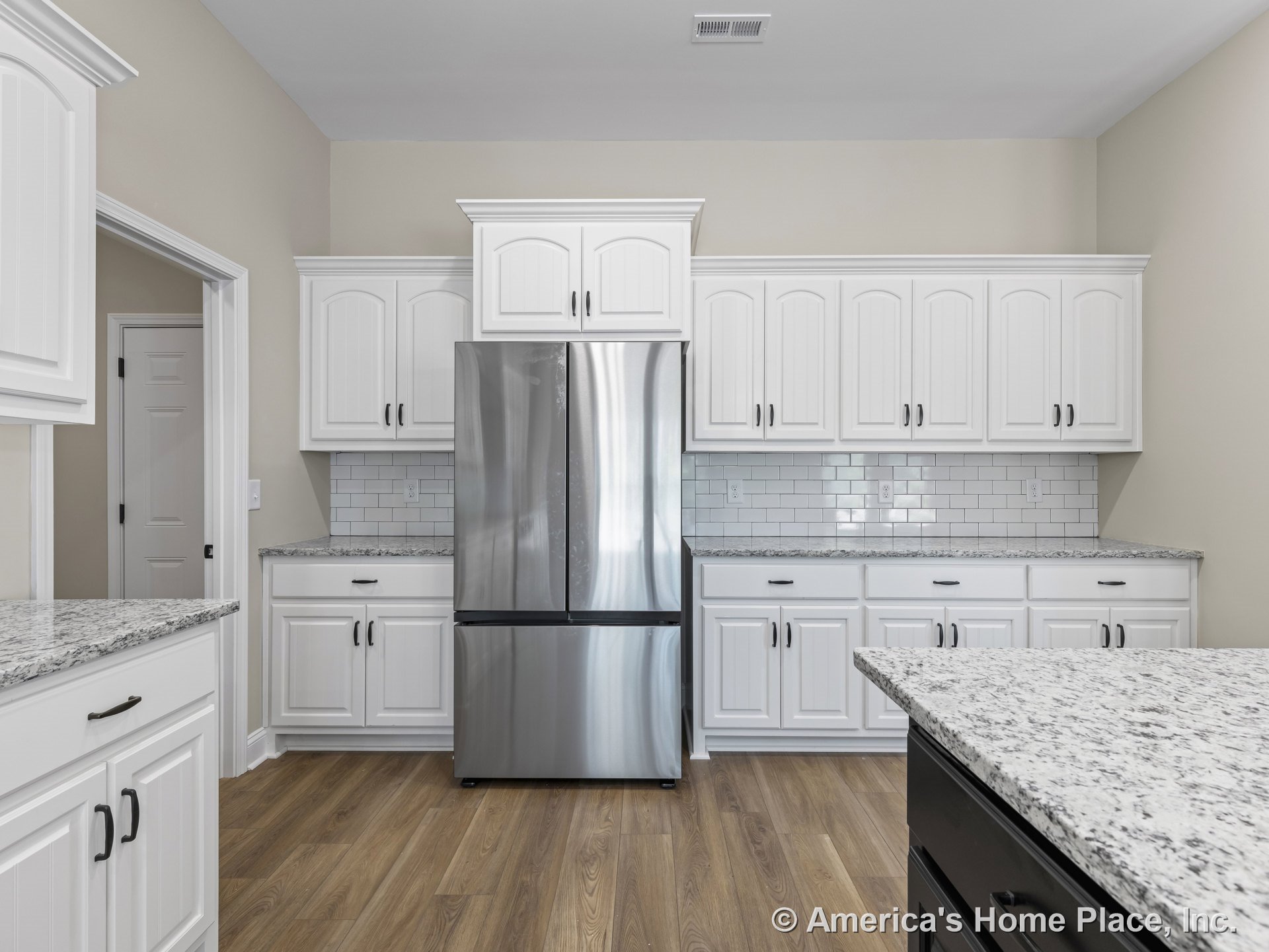 White upper and lower cabinets with granite countertops, subway tile backsplash, stainless steel refrigerator, wood-look flooring, and recessed ceiling vent.